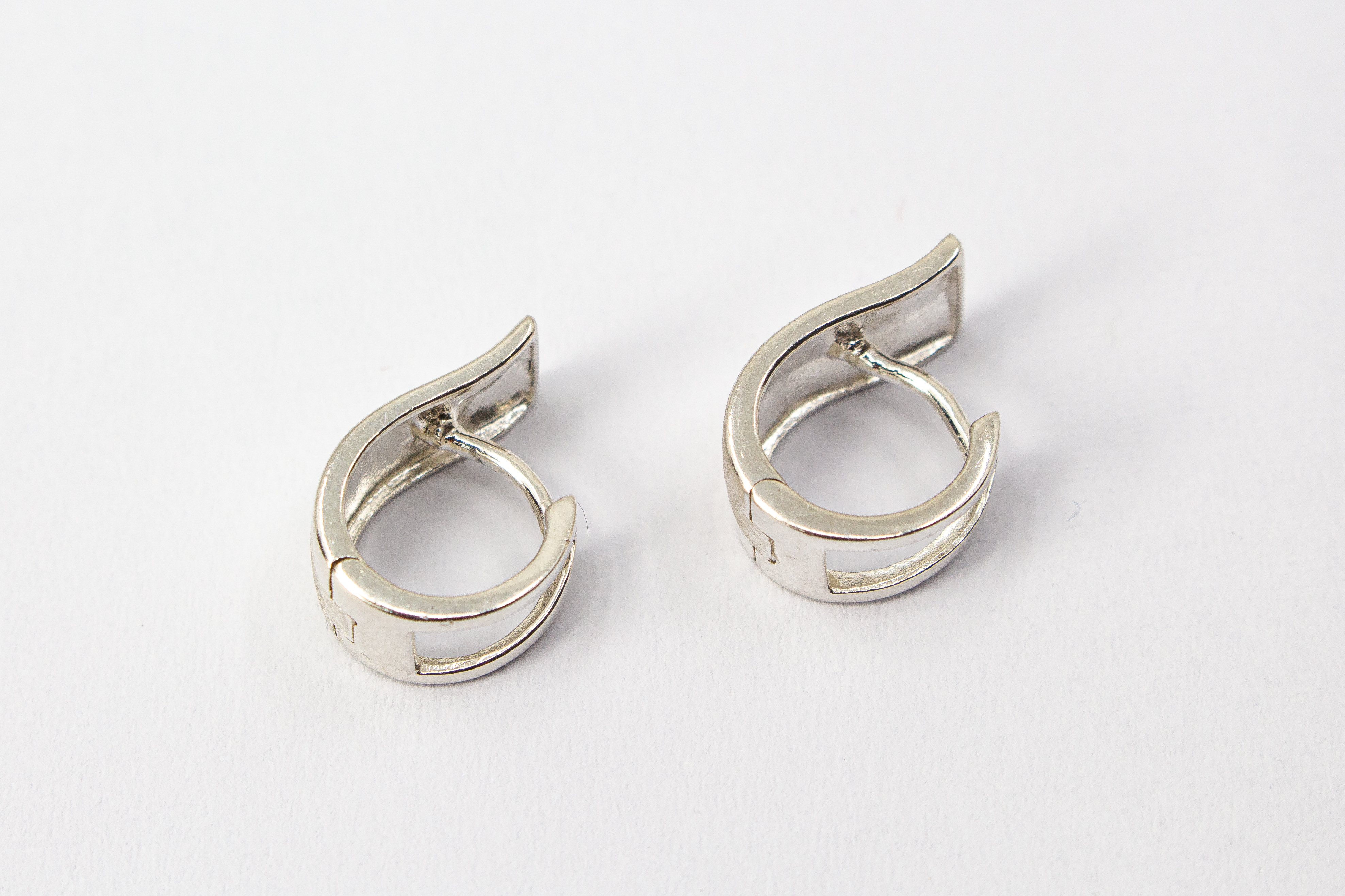 Breite Klappcreolen aus 925er Silber mit einer schwungvoll hochgezogenen, eismattierten Vorderseite und glänzend polierten Kanten im Onlineshop von Goldschmiede Regina Kraus.