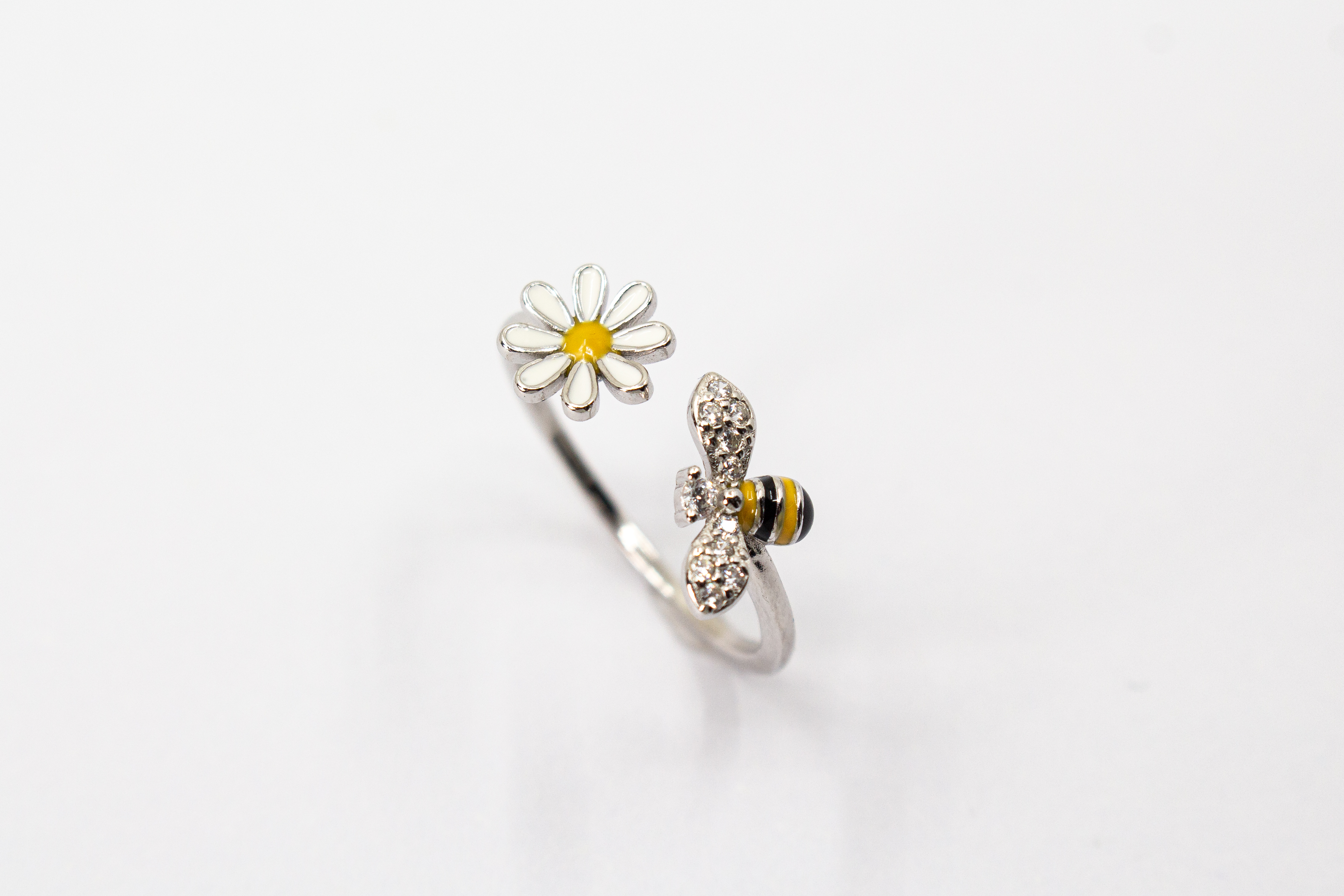 Offener Ring „Blütenbesuch“ aus rhodiniertem 925er Sterlingsilber mit Emaille-Blüte, funkelnder Biene und weißen Zirkonia.