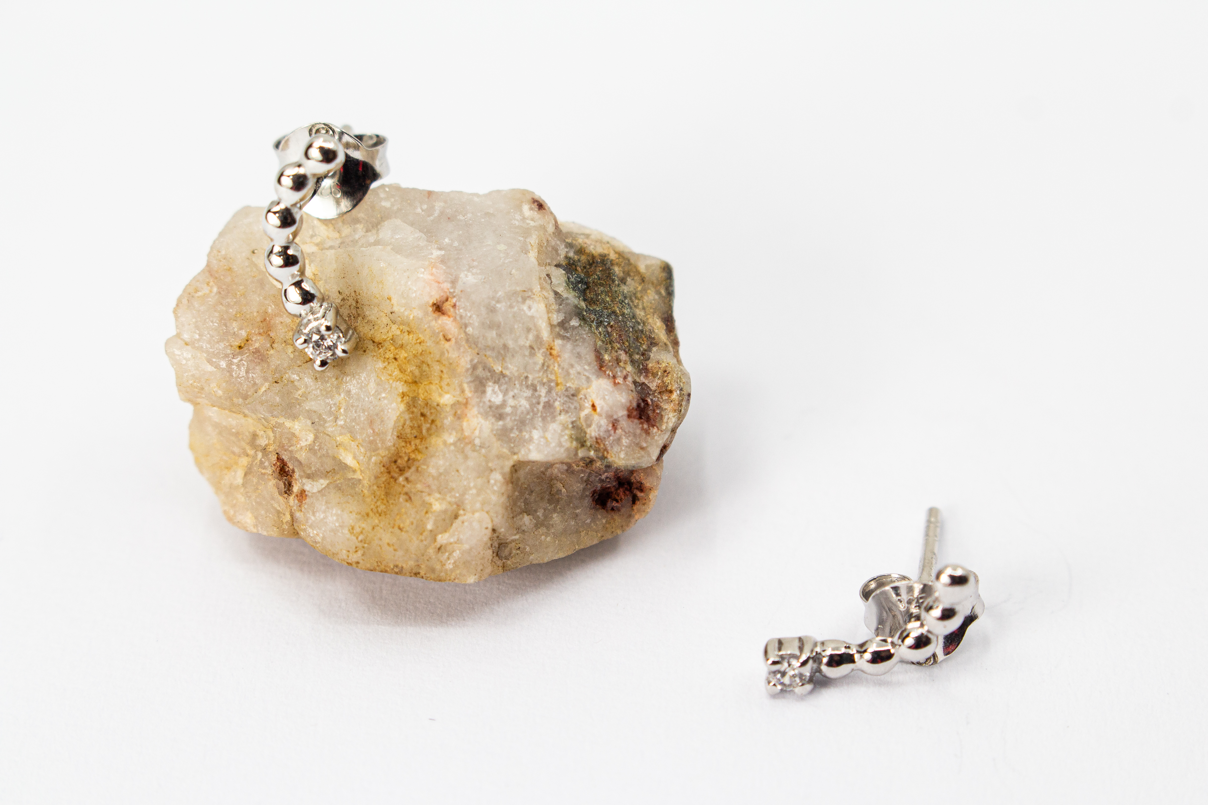 Moderne Ohrstecker aus rhodiniertem 925er Silber mit einem geschwungenen Bogen aus feinen Silberkugeln und funkelnden Zirkoniasteinen im Onlineshop von Goldschmiede Regina Kraus.