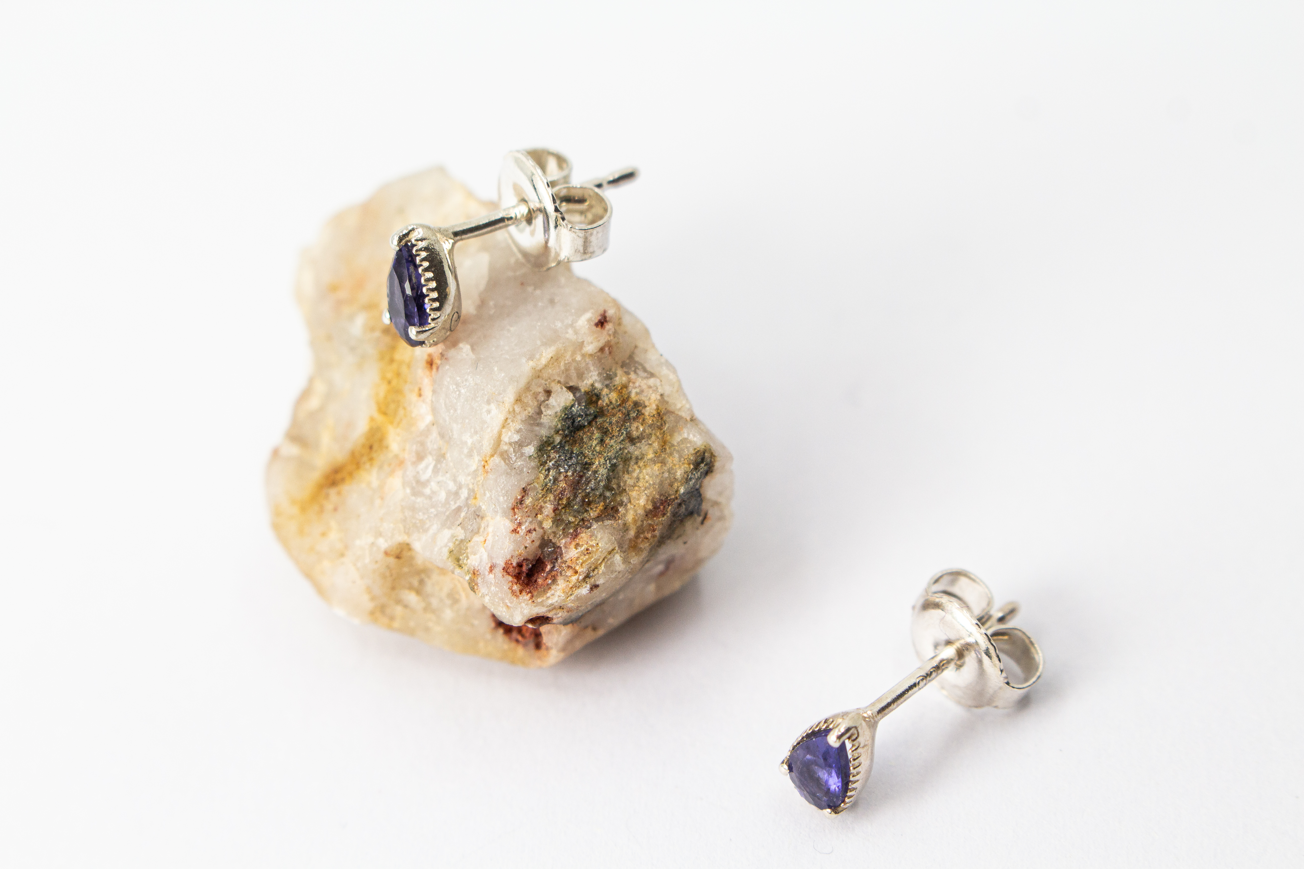 Paar filigrane Ohrstecker aus glänzendem 925 Sterling Silber mit kleinen, tropfenförmigen, blau-violetten Iolith-Edelsteinen in einer fein verzierten Fassung aus dem Online-Shop der Goldschmiede Regina Kraus.
