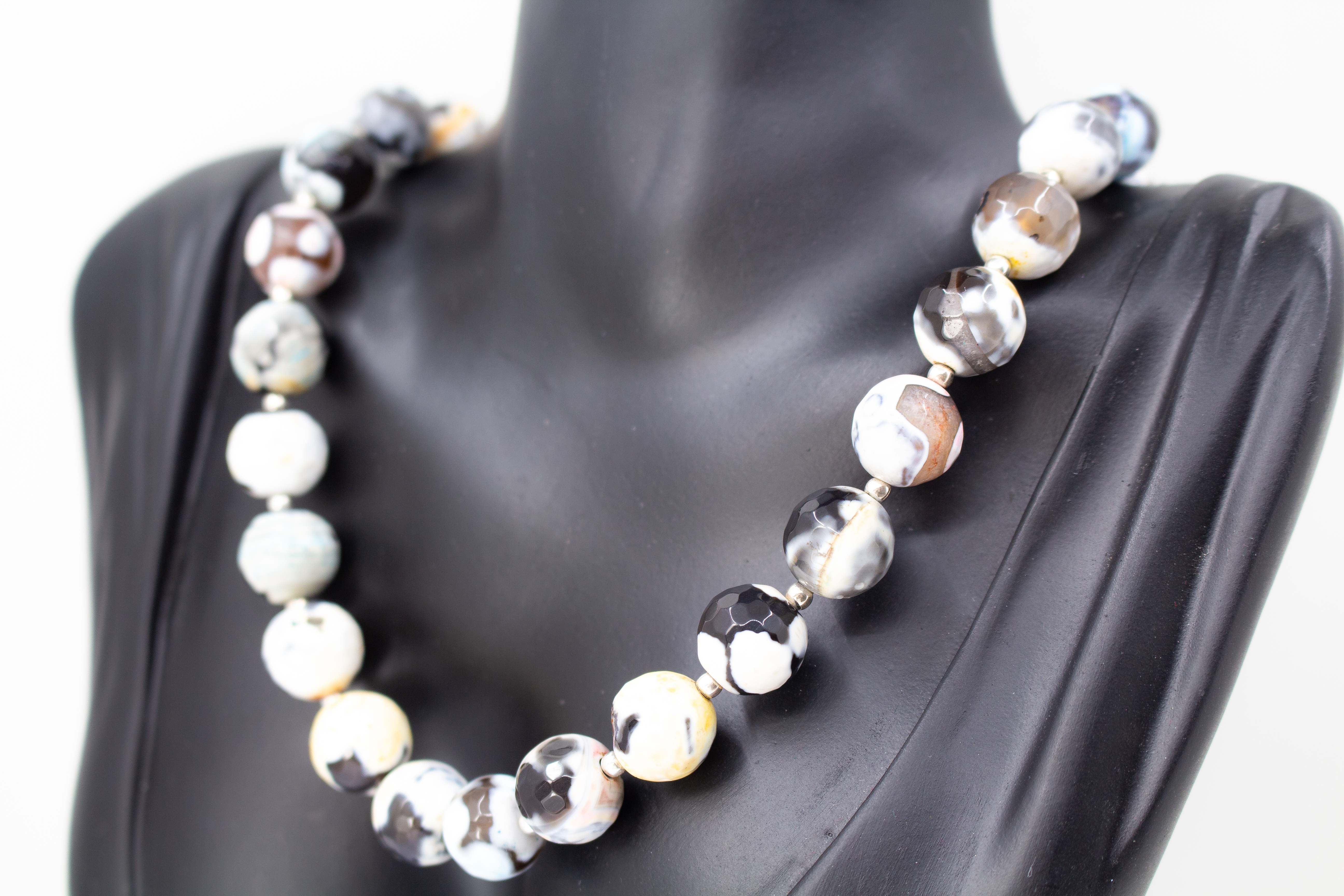 Ein handgefertigtes Collier aus bunt gemusterten, runden Feuerachat-Perlen mit kleinen silbernen Zwischenelementen und Magnetschließe