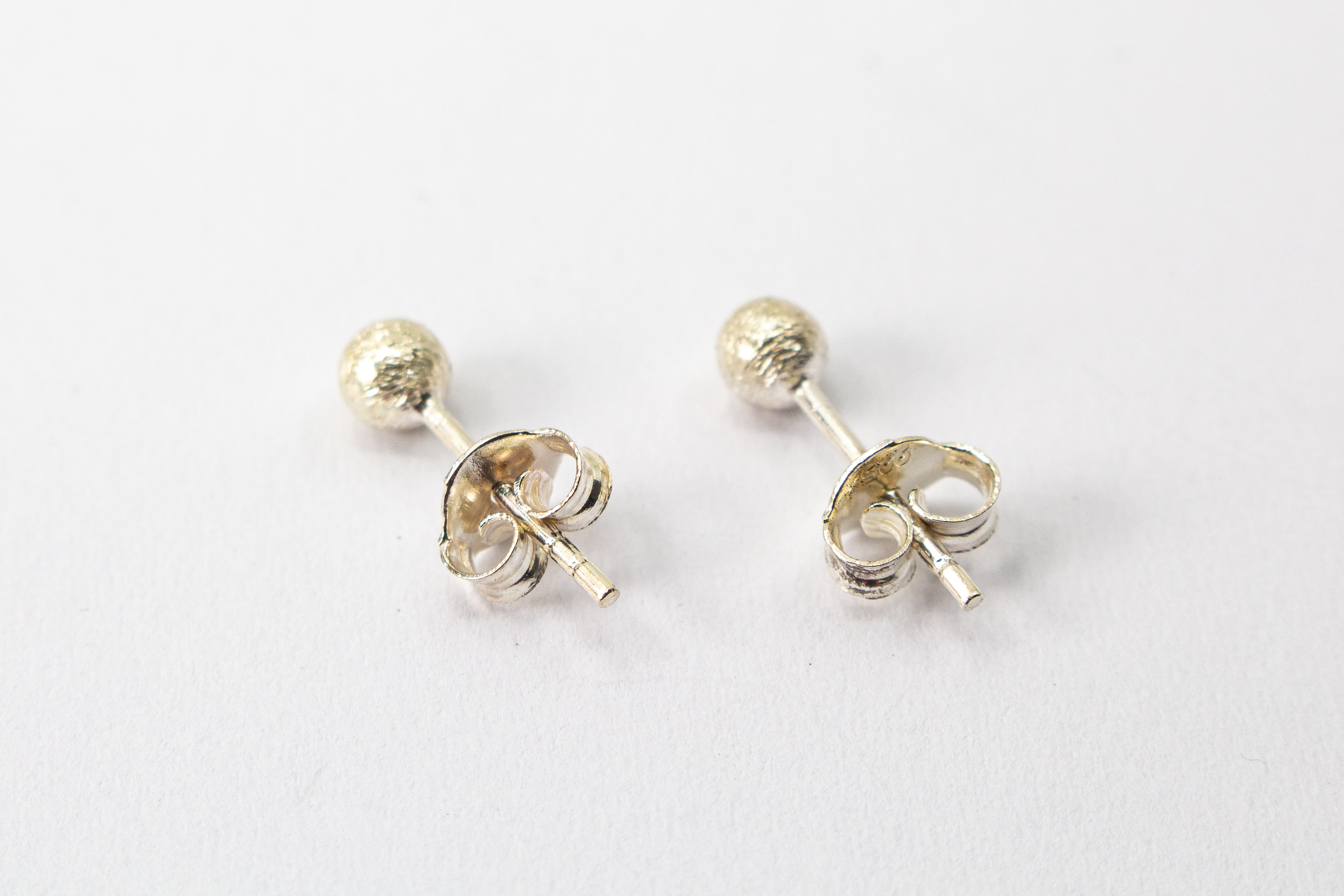 Klassische Kugel-Ohrstecker aus Silber mit mattierter, strukturierter Oberfläche im Onlineshop von Goldschmiede Regina Kraus.