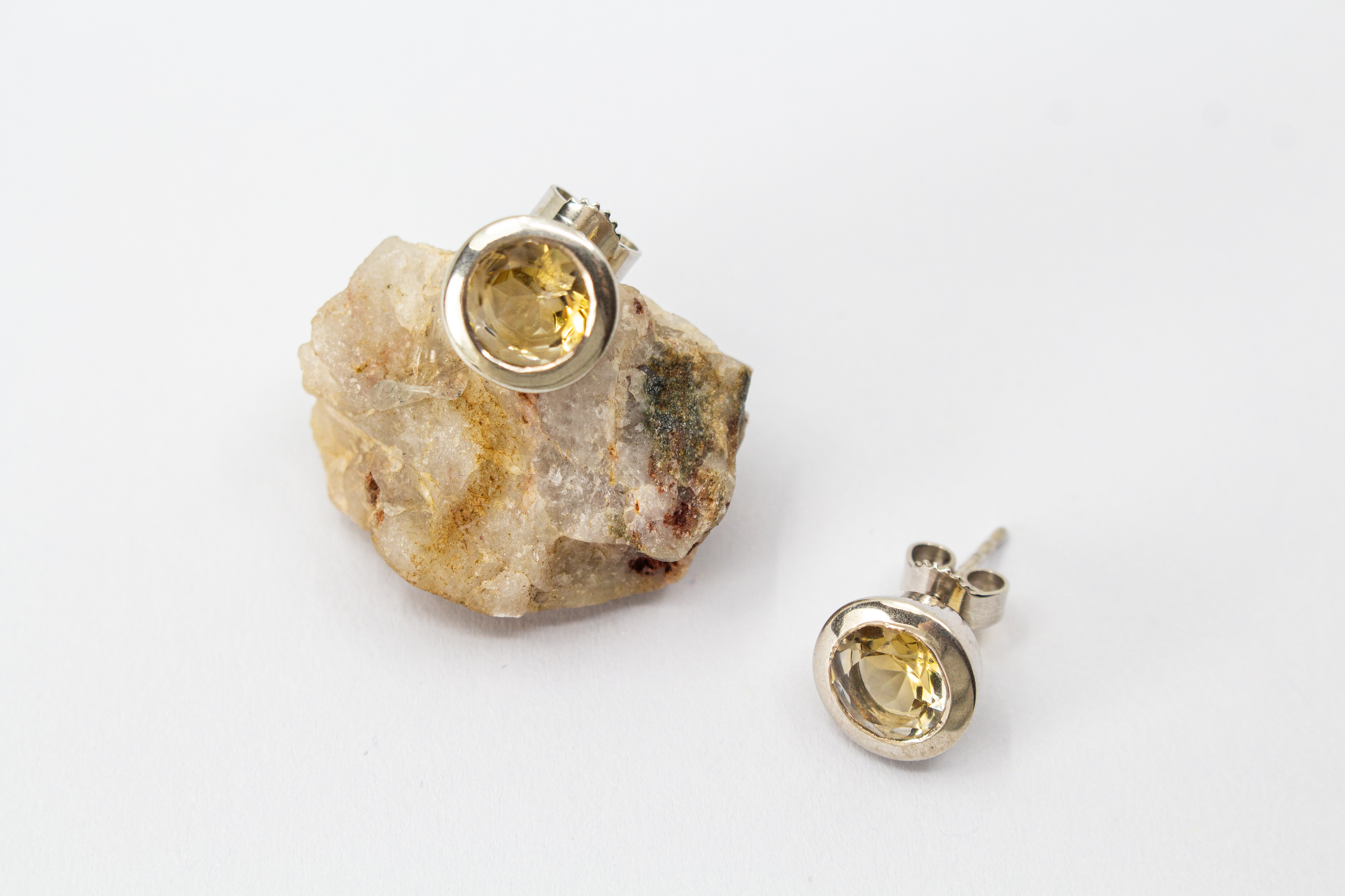 klassische, runde Ohrstecker aus glänzendem 925 Sterling Silber mit einem facettierten, hellgelben Citrin-Edelstein in einer glatten Zargenfassung aus dem Online-Shop der Goldschmiede Regina Kraus.