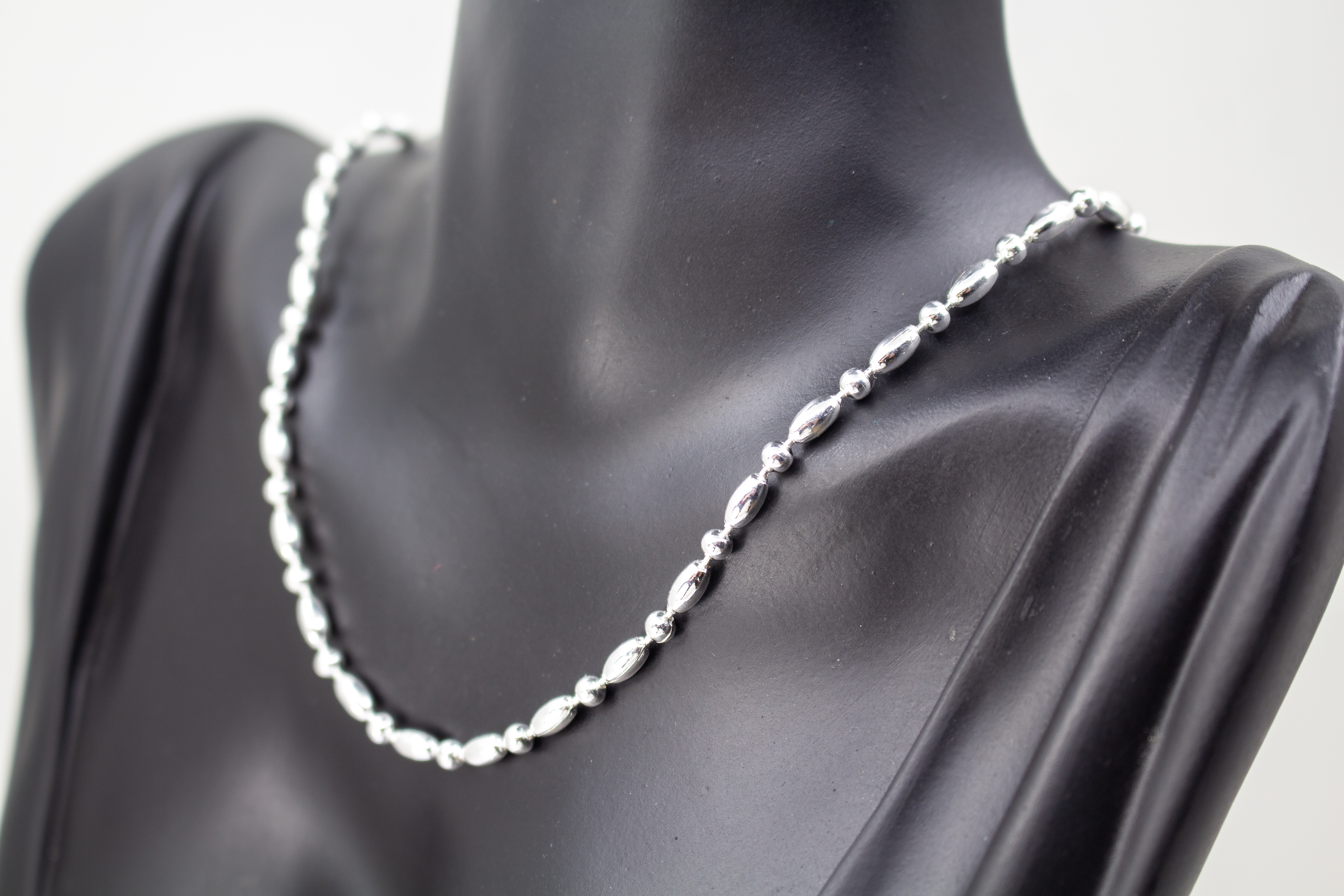Filigrane Silberkette aus hochglanzpoliertem 925er Sterlingsilber mit einem rhythmischen Wechsel aus Oliven- und Kugel-Elementen auf hellem Untergrund, exklusiv erhältlich im Schmuck-Onlineshop der Goldschmiede Regina Kraus.