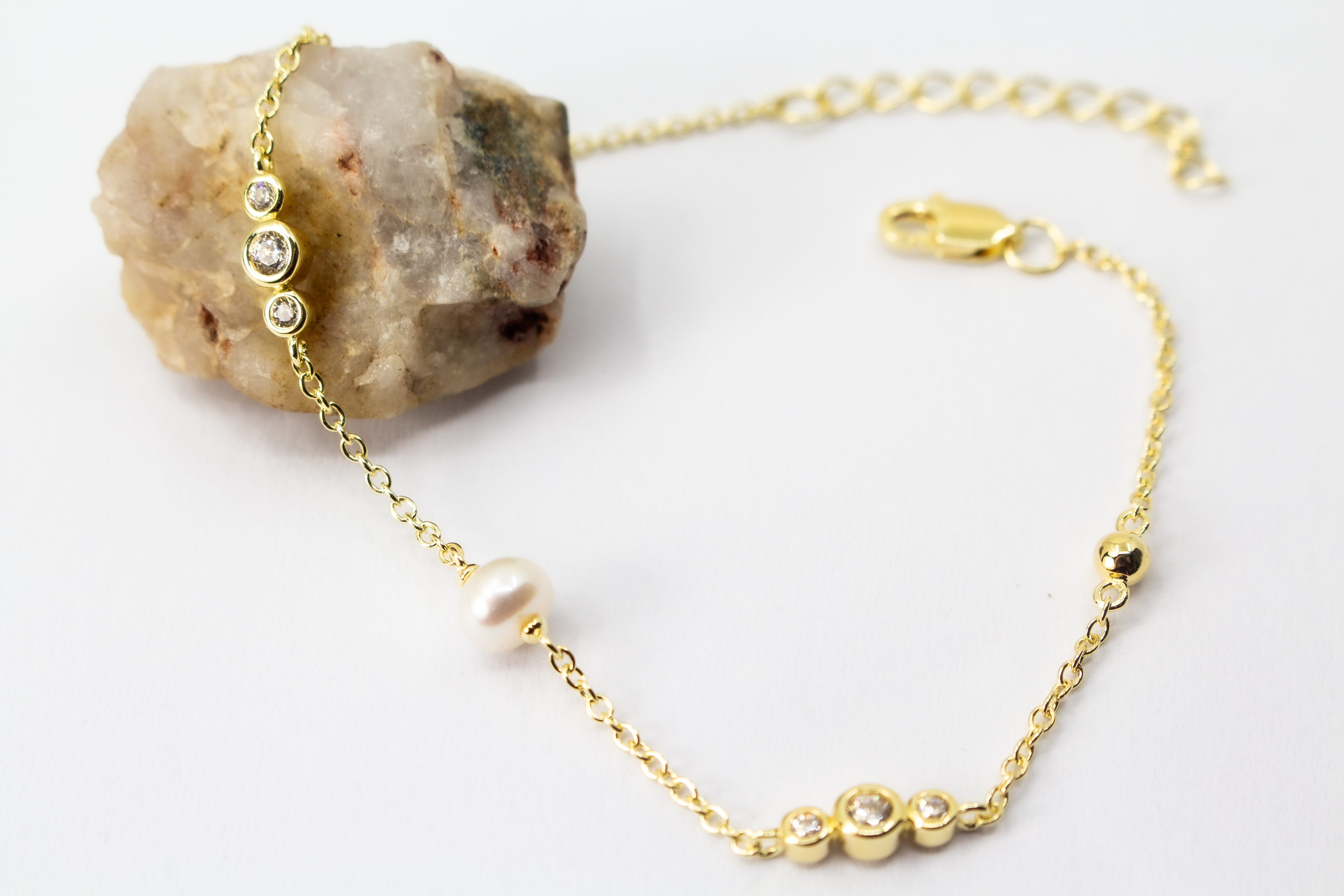 Edles Armband der Goldschmiede Regina Kraus aus vergoldetem 925er Silber mit einer zentralen Süßwasserperle, flankiert von funkelnden Zirkonia-Elementen und kleinen Goldkugeln