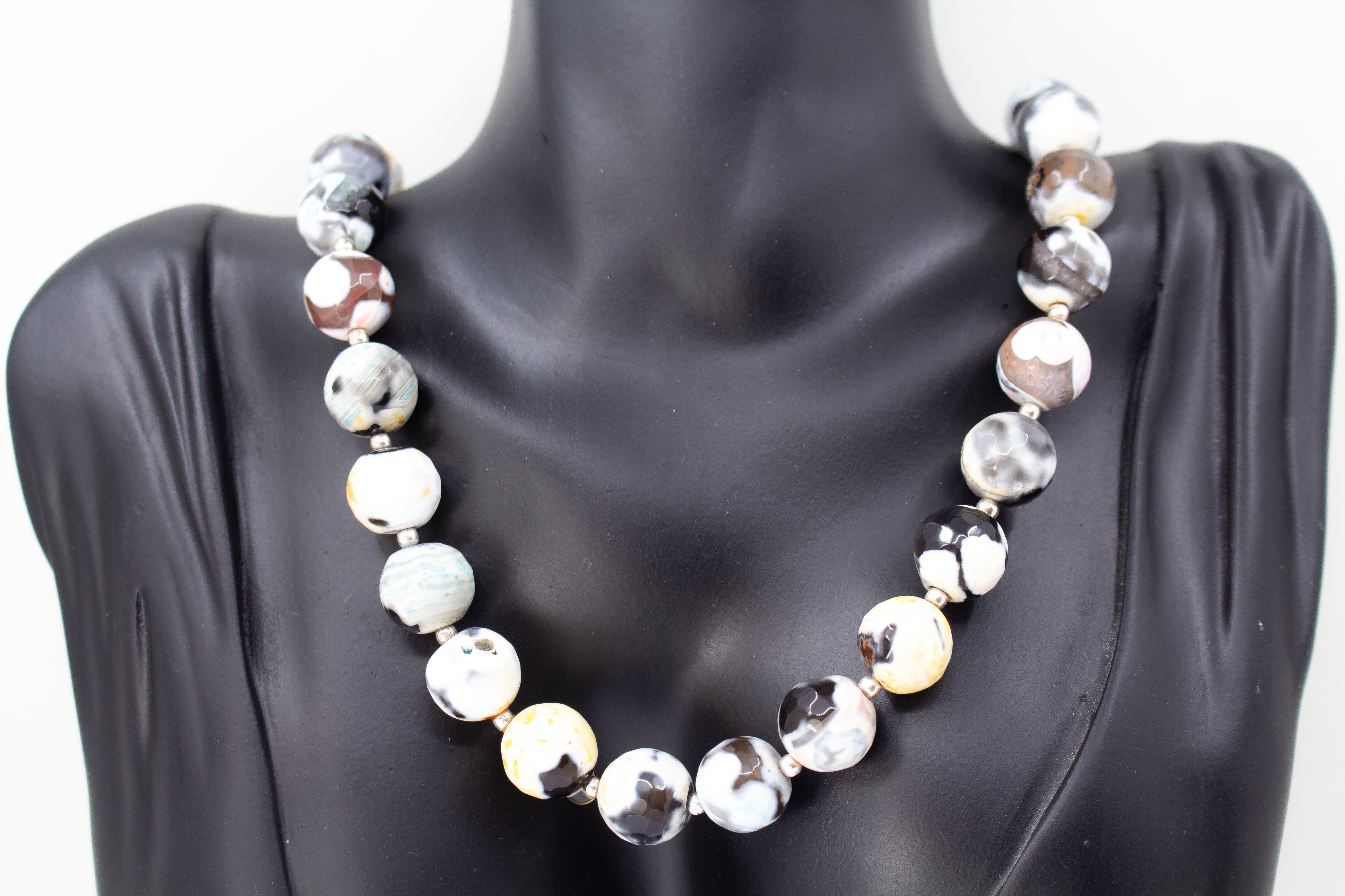 Ein handgefertigtes Collier aus bunt gemusterten, runden Feuerachat-Perlen mit kleinen silbernen Zwischenelementen und Magnetschließe