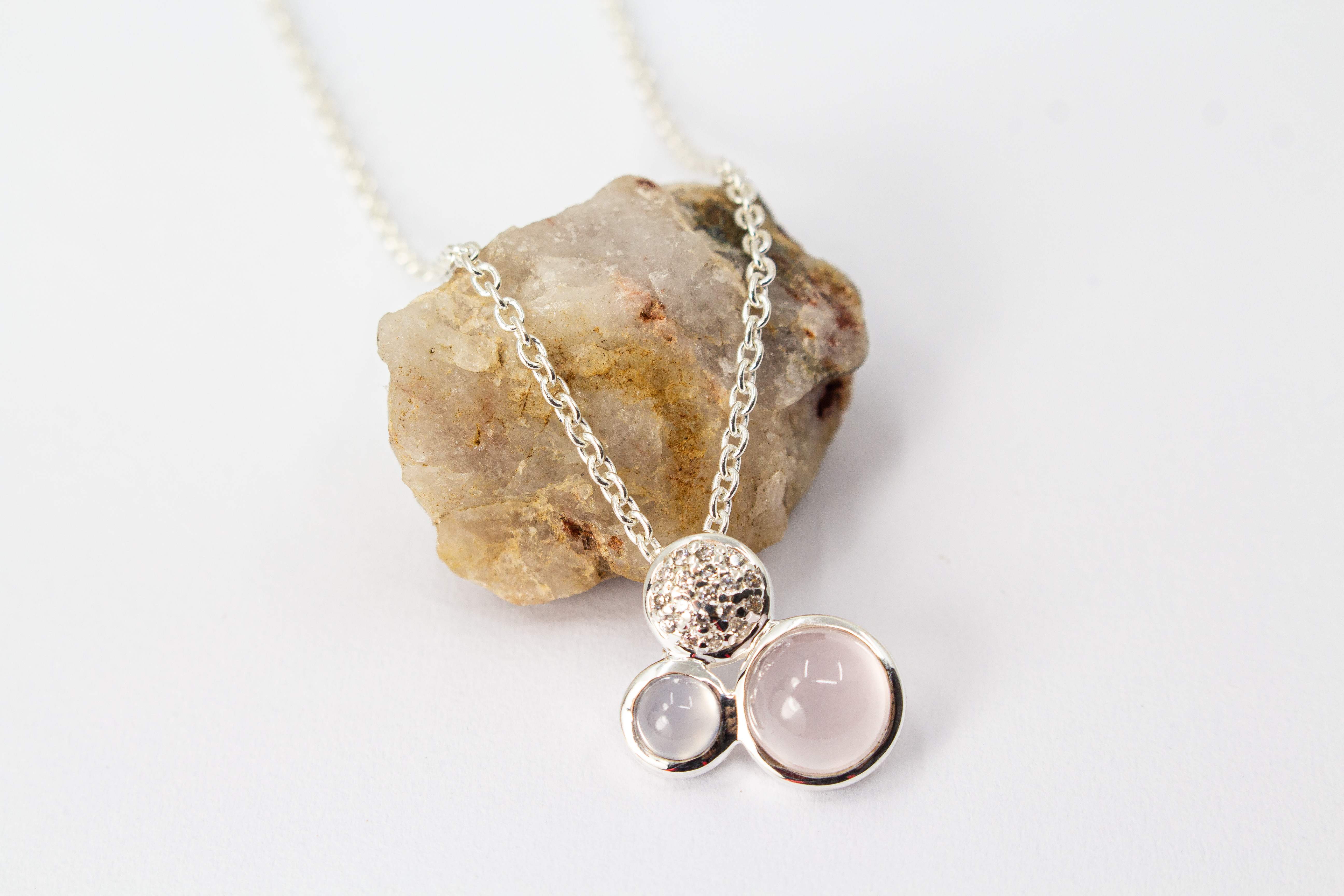 Filigrane Damen-Halskette aus 925er Sterling Silber mit einem dreiteiligen Anhänger, bestehend aus einem runden Rosenquarz-Cabochon in Zartrosa, einem kleineren hellblauen Chalcedon und einem rund gefassten Element mit funkelndem Zirkonia-Besatz