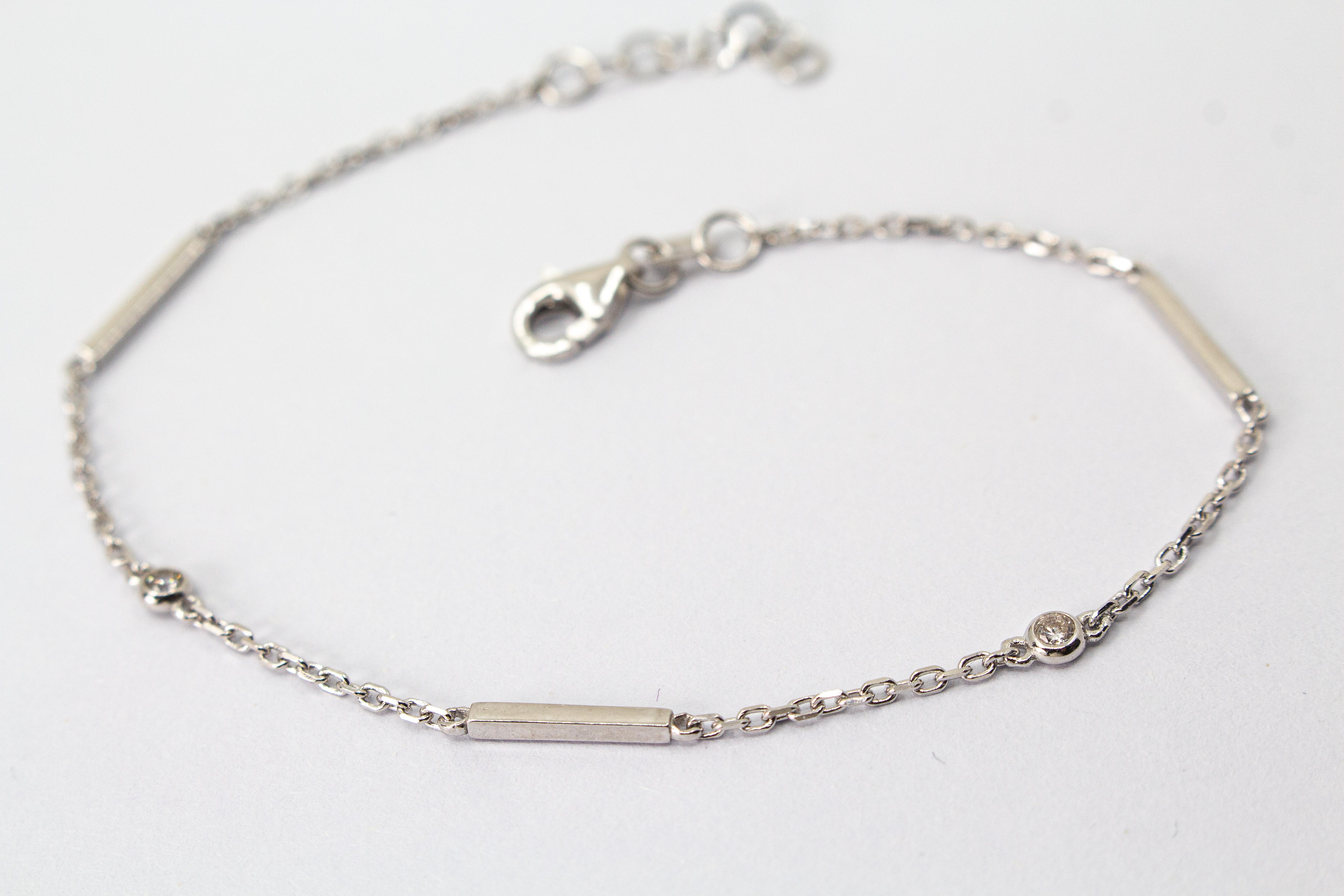 Filigranes, rhodiniertes Damen-Armkettchen aus 925 Sterling Silber mit kleinen, rund gefassten Zirkonia-Steinen und glatten, minimalistischen Stäbchen-Elementen aus dem Online-Shop der Goldschmiede Regina Kraus.