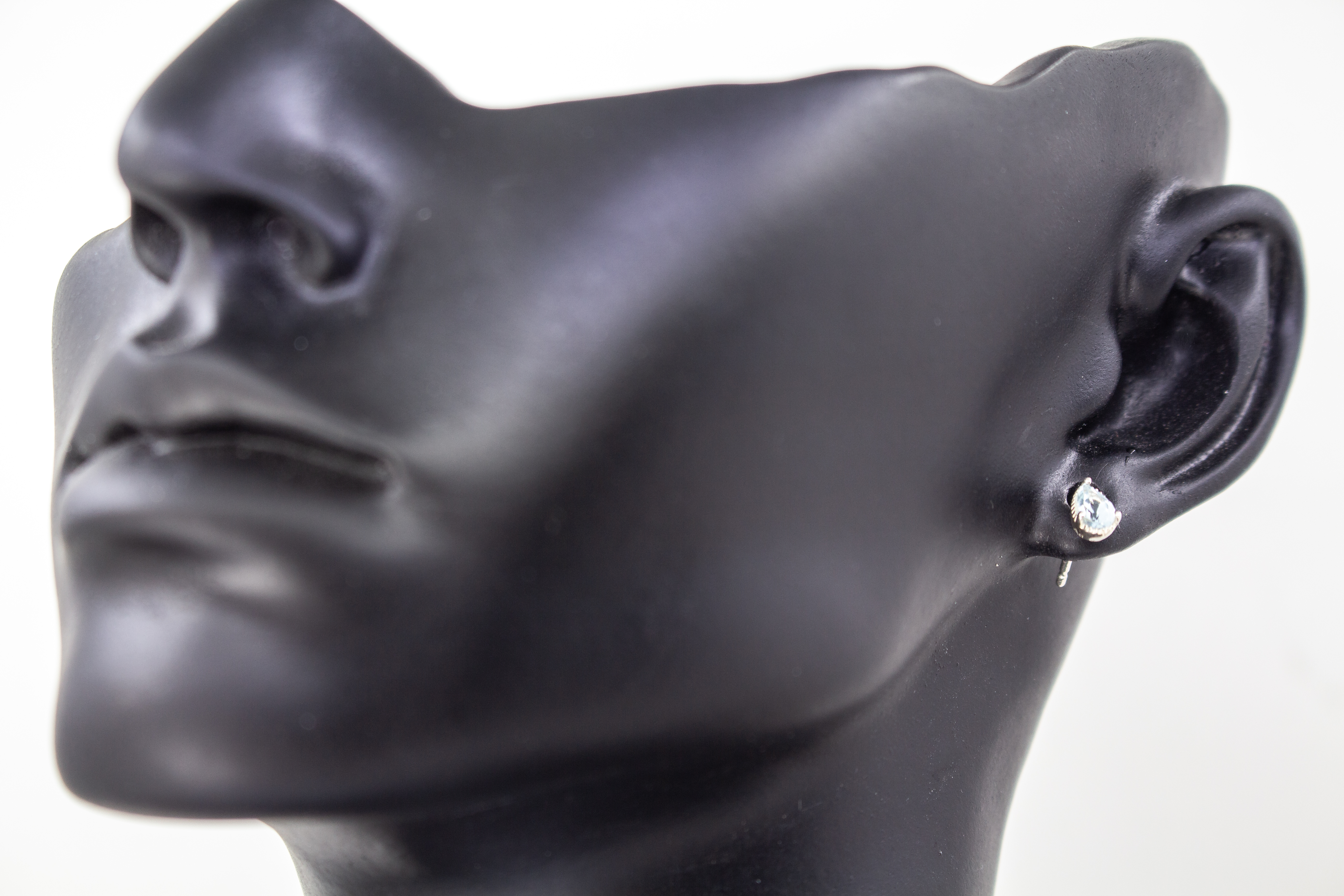 filigrane Ohrstecker aus glänzendem 925 Sterling Silber mit kleinen, tropfenförmigen, hellblauen Topas-Edelsteinen in einer fein verzierten Krappenfassung aus dem Online-Shop der Goldschmiede Regina Kraus.