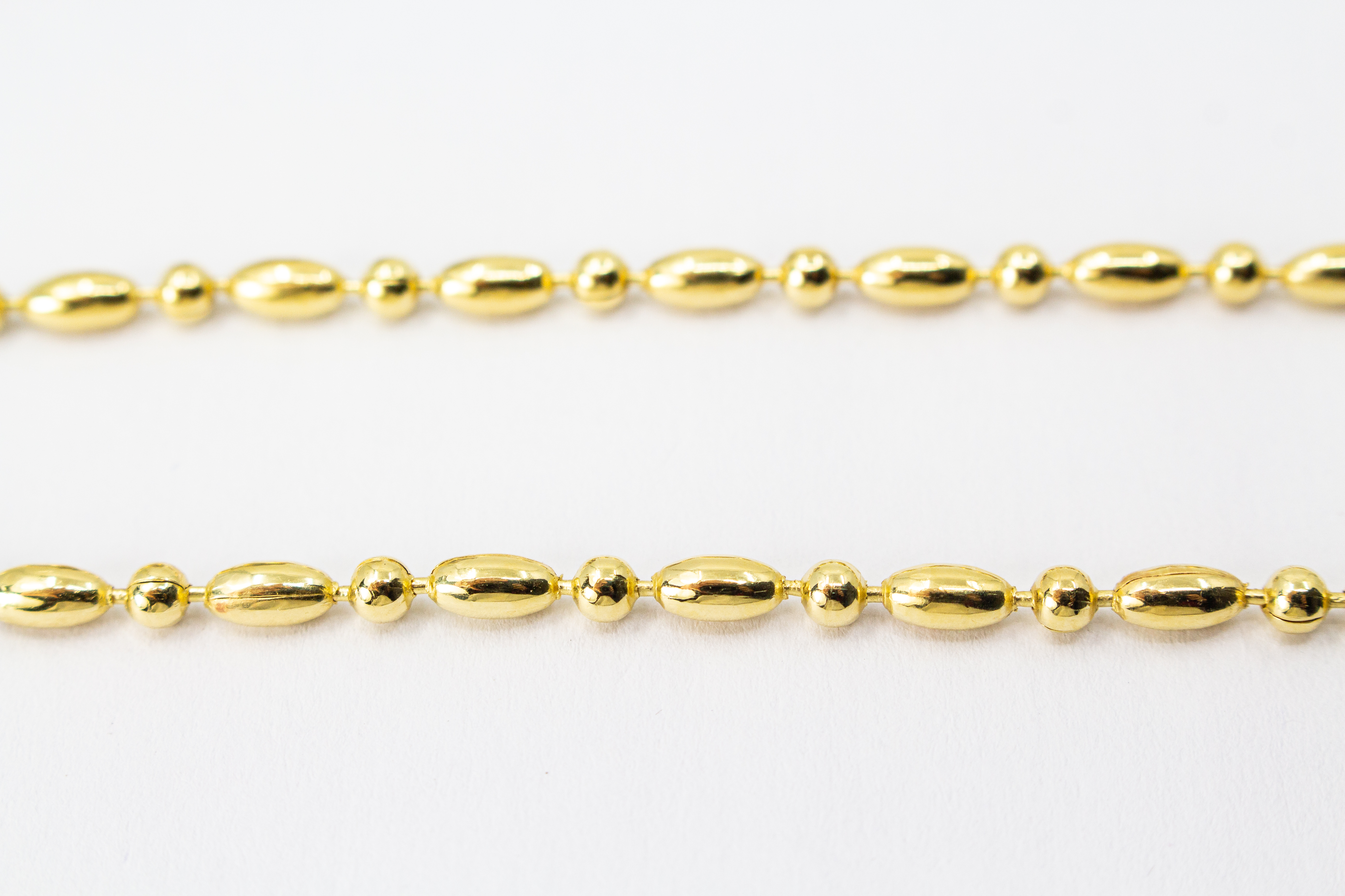 Elegantes, hochwertig vergoldetes Collier aus 925er Sterlingsilber mit einer 20 Mikron Vergoldung, gestaltet in einem rhythmischen Wechsel aus polierten Oliven- und Kugel-Elementen auf hellem Hintergrund, aus dem Schmuck-Onlineshop der Goldschmiede Regina