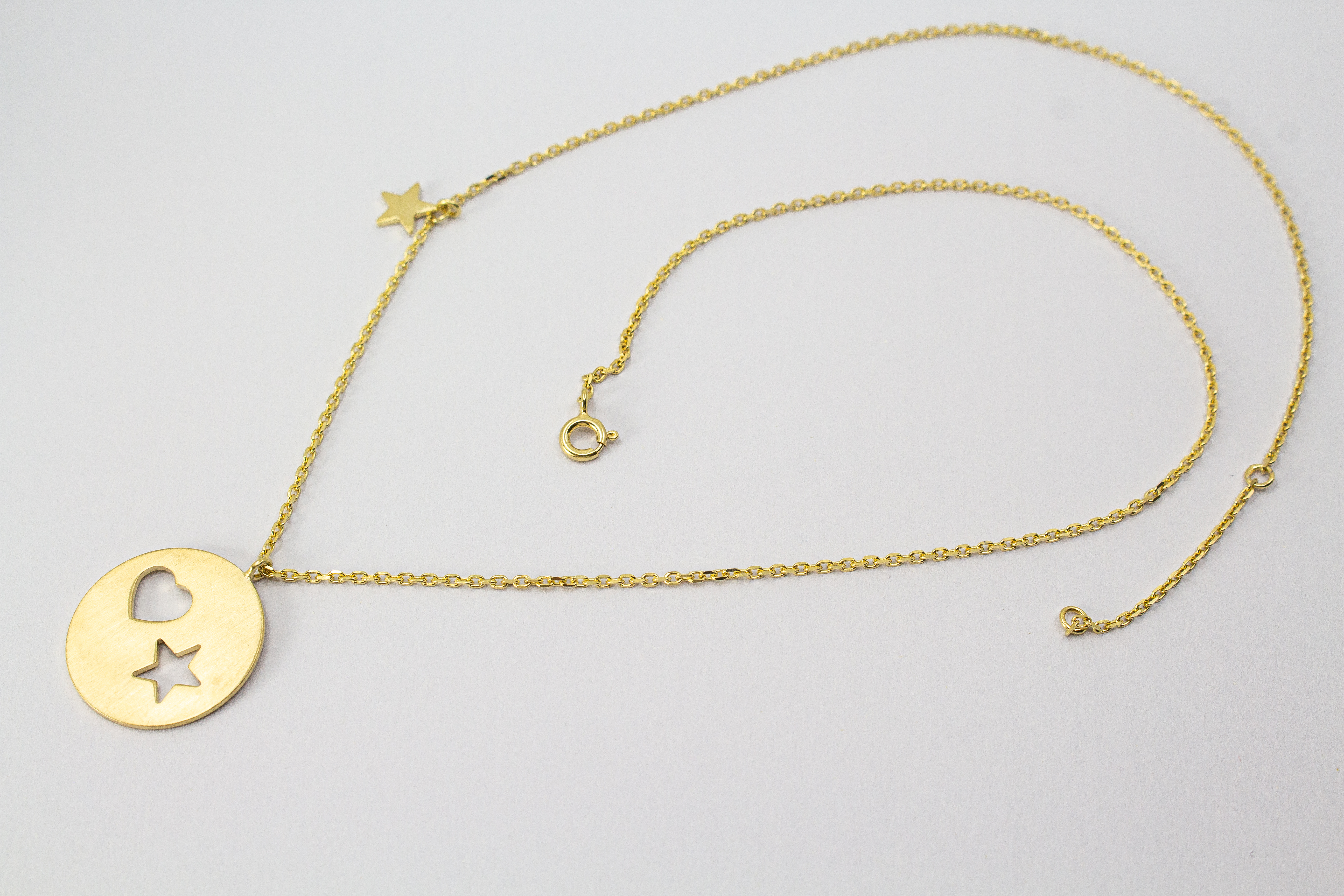 Collier „Sternenliebe“ aus vergoldetem 925er Sterlingsilber mit rundem Anhänger, Herz- und Sternmotiv sowie zusätzlichem Sternanhänger.