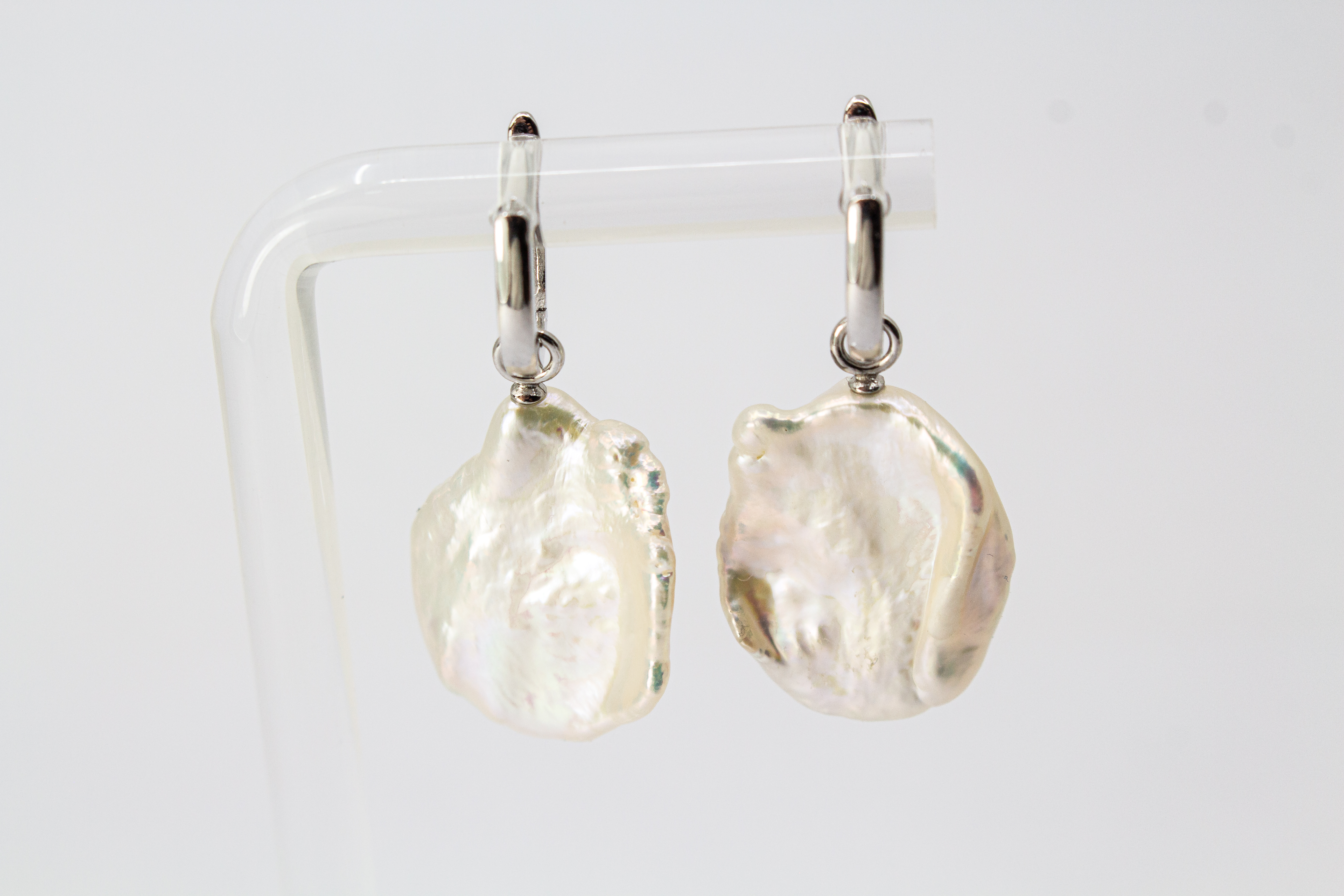 Ein Paar wandelbare Wechselcreolen „Meeresskulptur“ aus rhodiniertem 925er Sterlingsilber von der Goldschmiede Regina Kraus. Die Ohrringe tragen abnehmbare Anhänger aus großen, flachen weißen Keshi-Zuchtperlen, die durch ihre organische Freiform wie eine