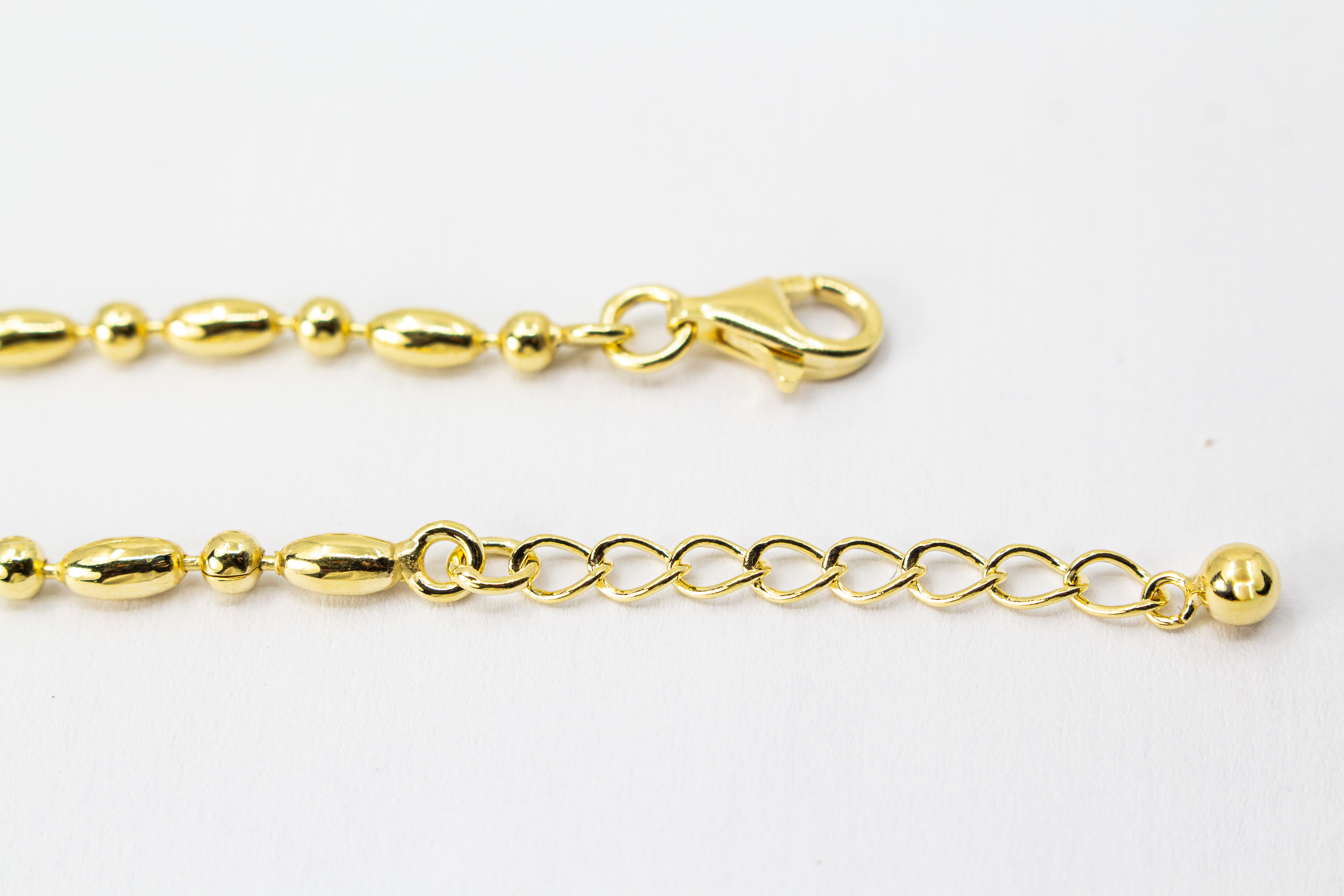 Filigranes, hochwertig vergoldetes Silberarmband (925er Silber, 20 Mikron Vergoldung) mit einem wechselnden Muster aus glänzenden Oliven- und Kugel-Elementen sowie Karabinerverschluss, erhältlich im Onlineshop der Goldschmiede Regina Kraus.