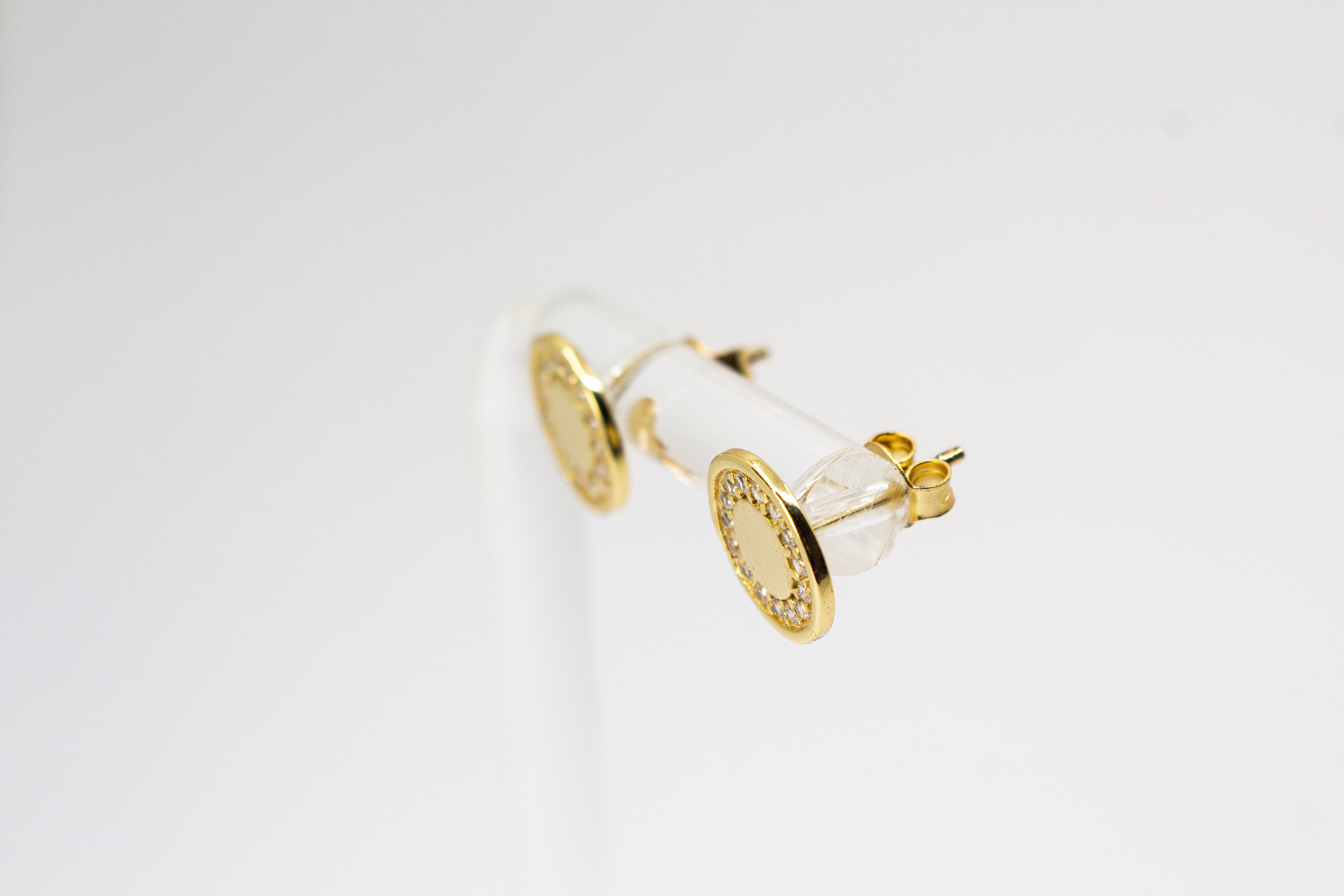 Runde, vergoldete Ohrstecker aus 925er Silber mit einer glatten Innenfläche und einem äußeren Kranz aus funkelnden Zirkoniasteinen im Onlineshop von Goldschmiede Regina Kraus.