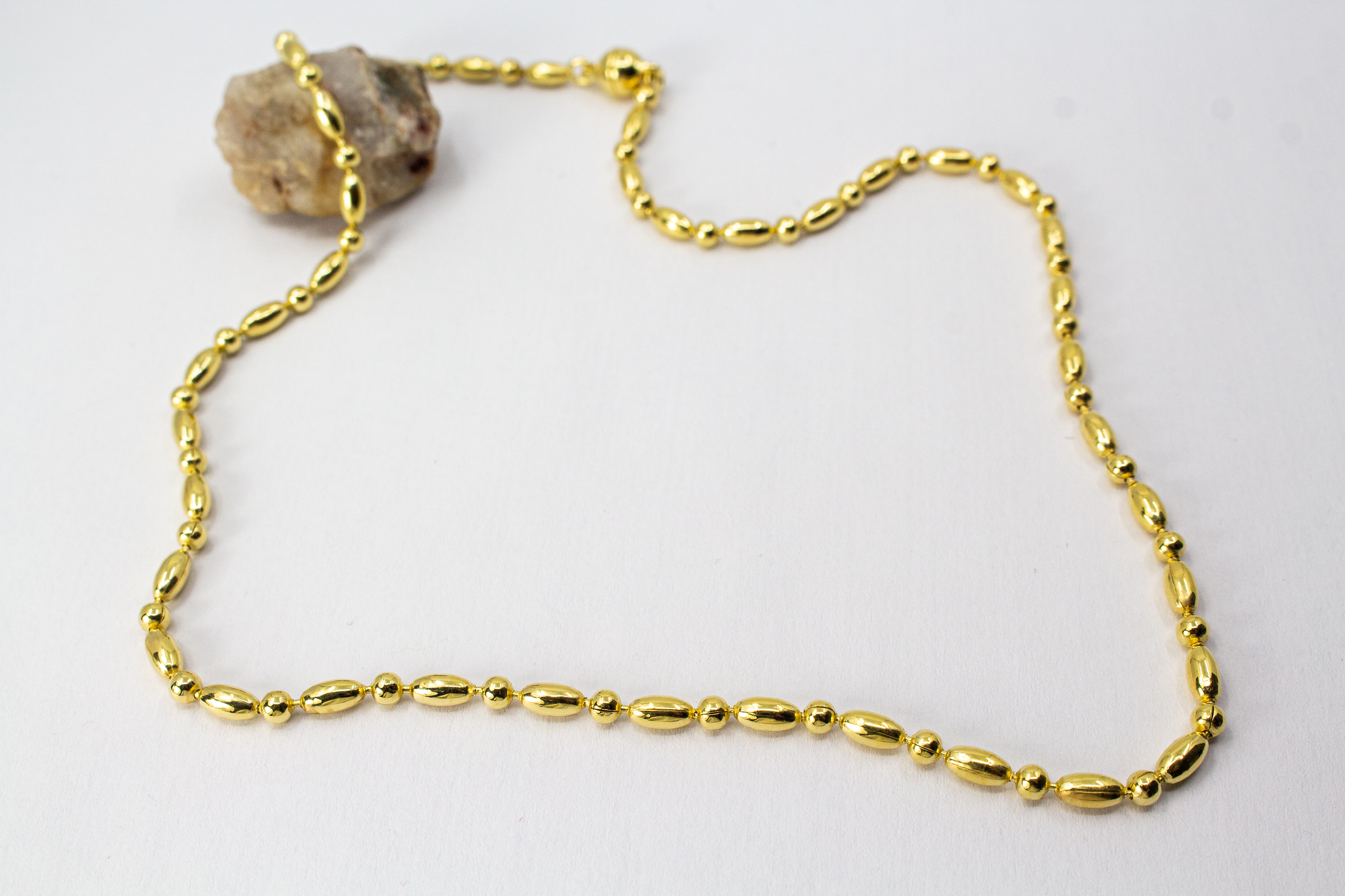 Elegantes, hochwertig vergoldetes Collier aus 925er Sterlingsilber mit einer 20 Mikron Vergoldung, gestaltet in einem rhythmischen Wechsel aus polierten Oliven- und Kugel-Elementen auf hellem Hintergrund, aus dem Schmuck-Onlineshop der Goldschmiede Regina
