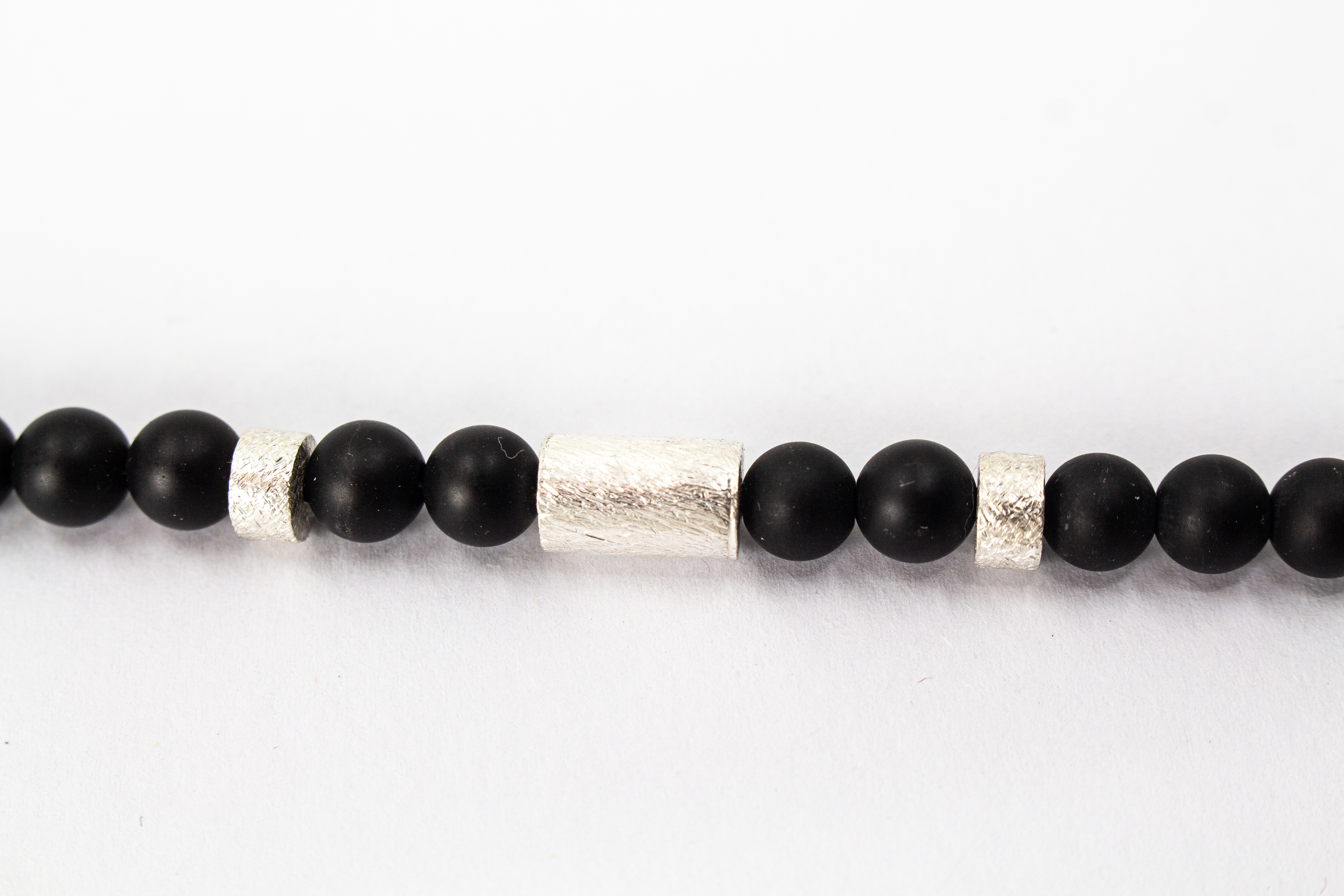 Herrenarmband „Dunkler Pol“ aus mattschwarzem Onyx mit markanten Zwischenteilen aus 925er Sterlingsilber.
