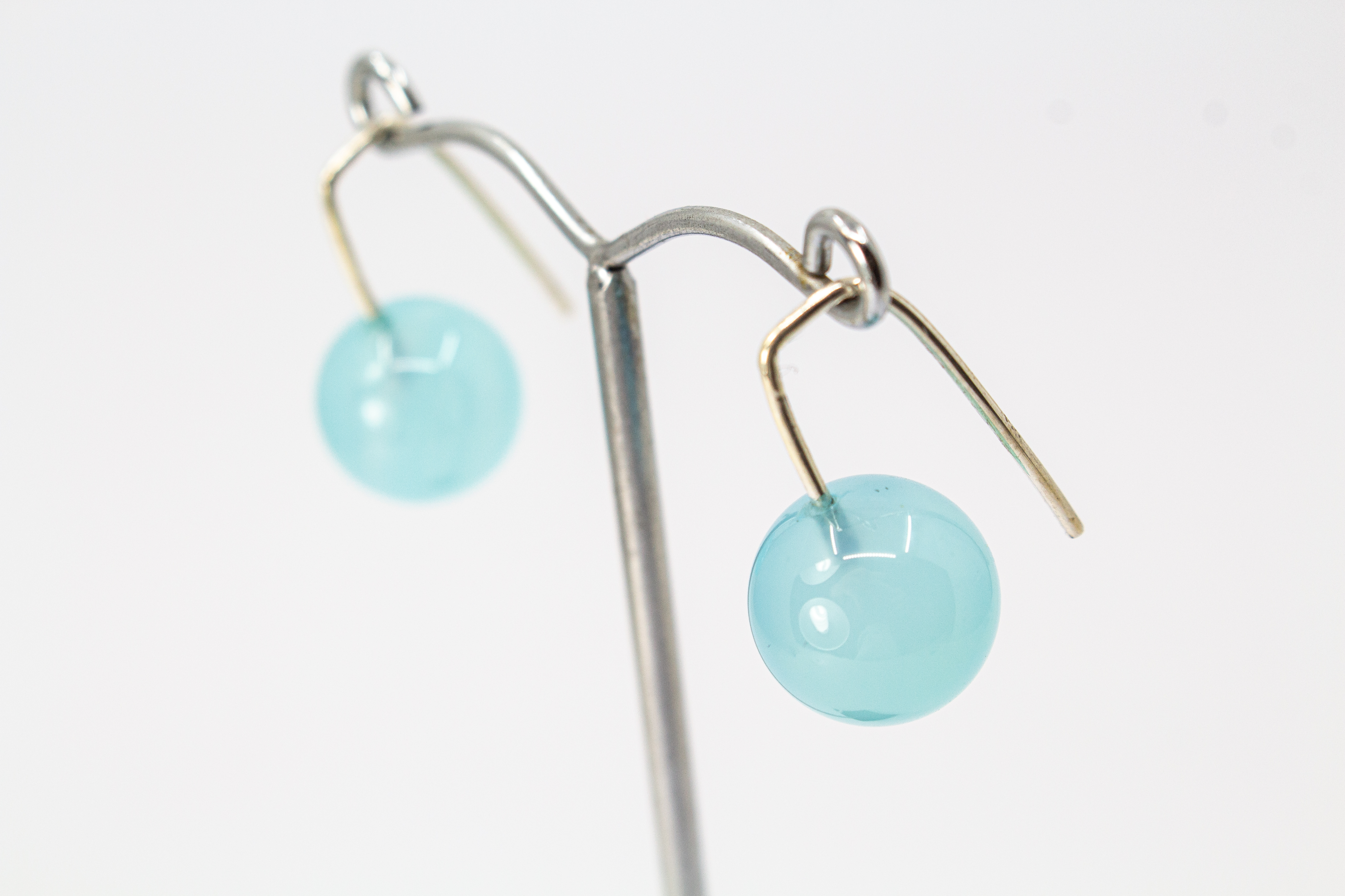Minimalistische Ohrhänger aus feinen 925 Sterling Silberbügeln mit je einer glatten, hellblauen Chalcedon-Edelsteinkugel aus dem Online-Shop der Goldschmiede Regina Kraus