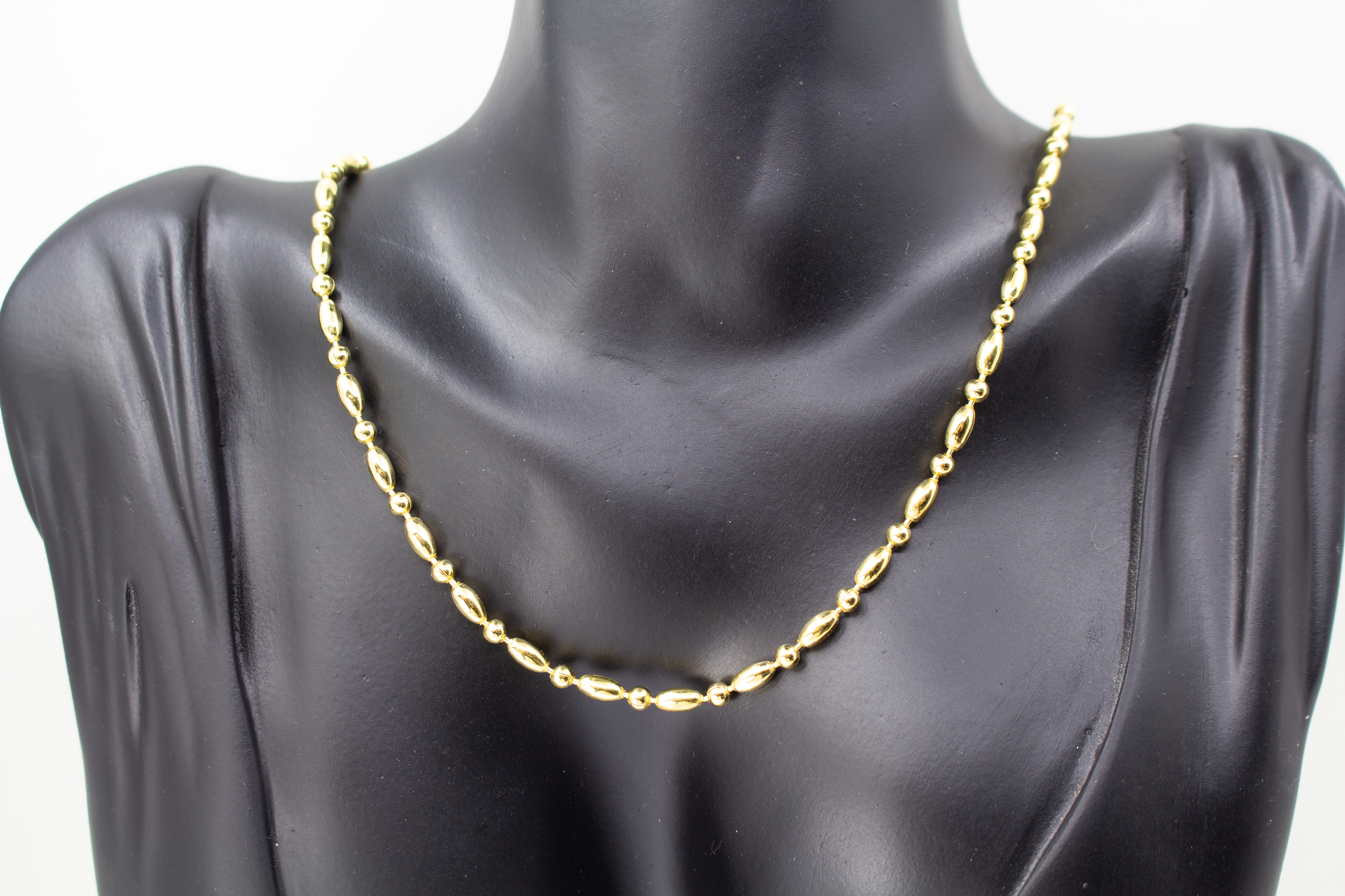 Elegantes, hochwertig vergoldetes Collier aus 925er Sterlingsilber mit einer 20 Mikron Vergoldung, gestaltet in einem rhythmischen Wechsel aus polierten Oliven- und Kugel-Elementen auf hellem Hintergrund, aus dem Schmuck-Onlineshop der Goldschmiede Regina
