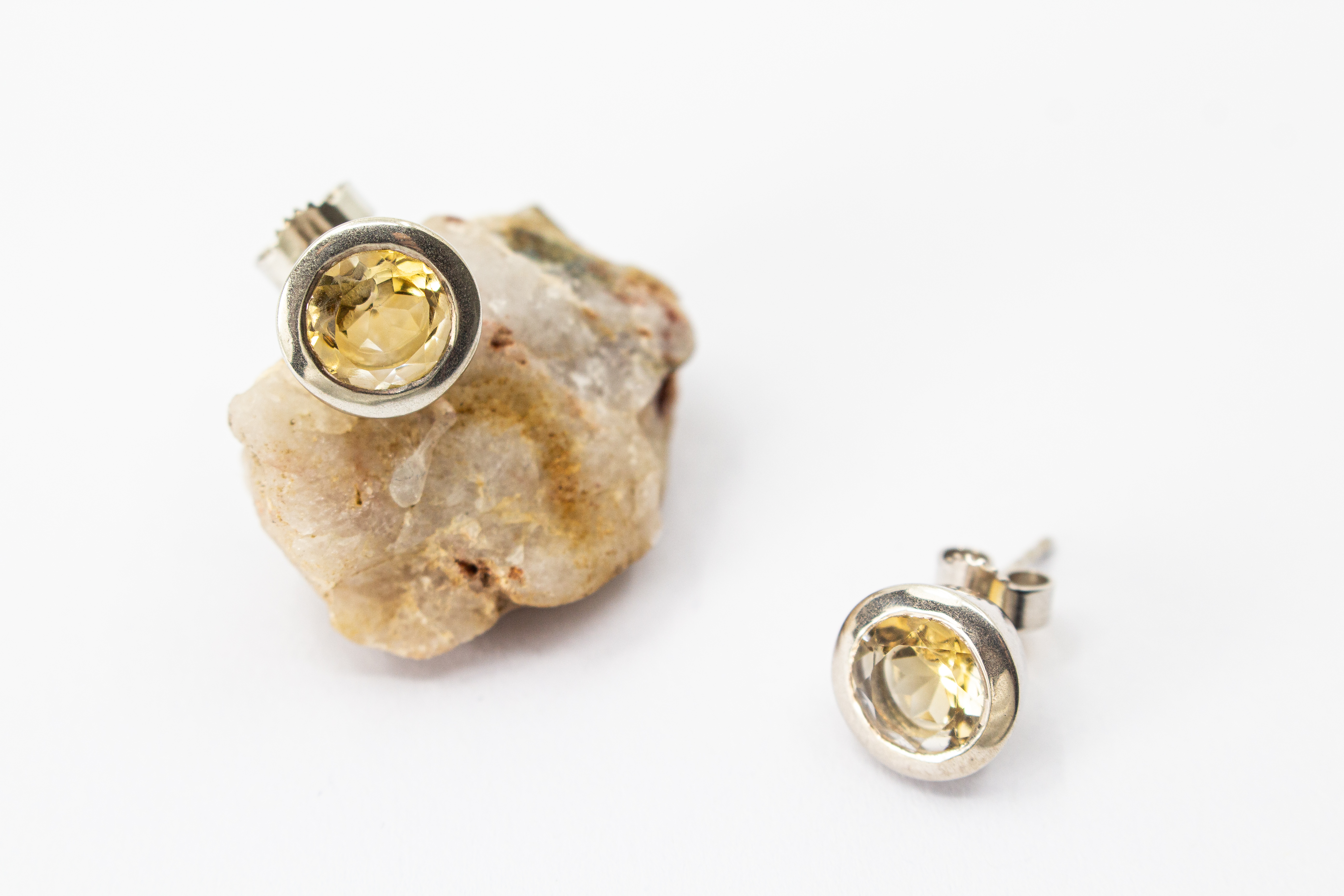 klassische, runde Ohrstecker aus glänzendem 925 Sterling Silber mit einem facettierten, hellgelben Citrin-Edelstein in einer glatten Zargenfassung aus dem Online-Shop der Goldschmiede Regina Kraus.