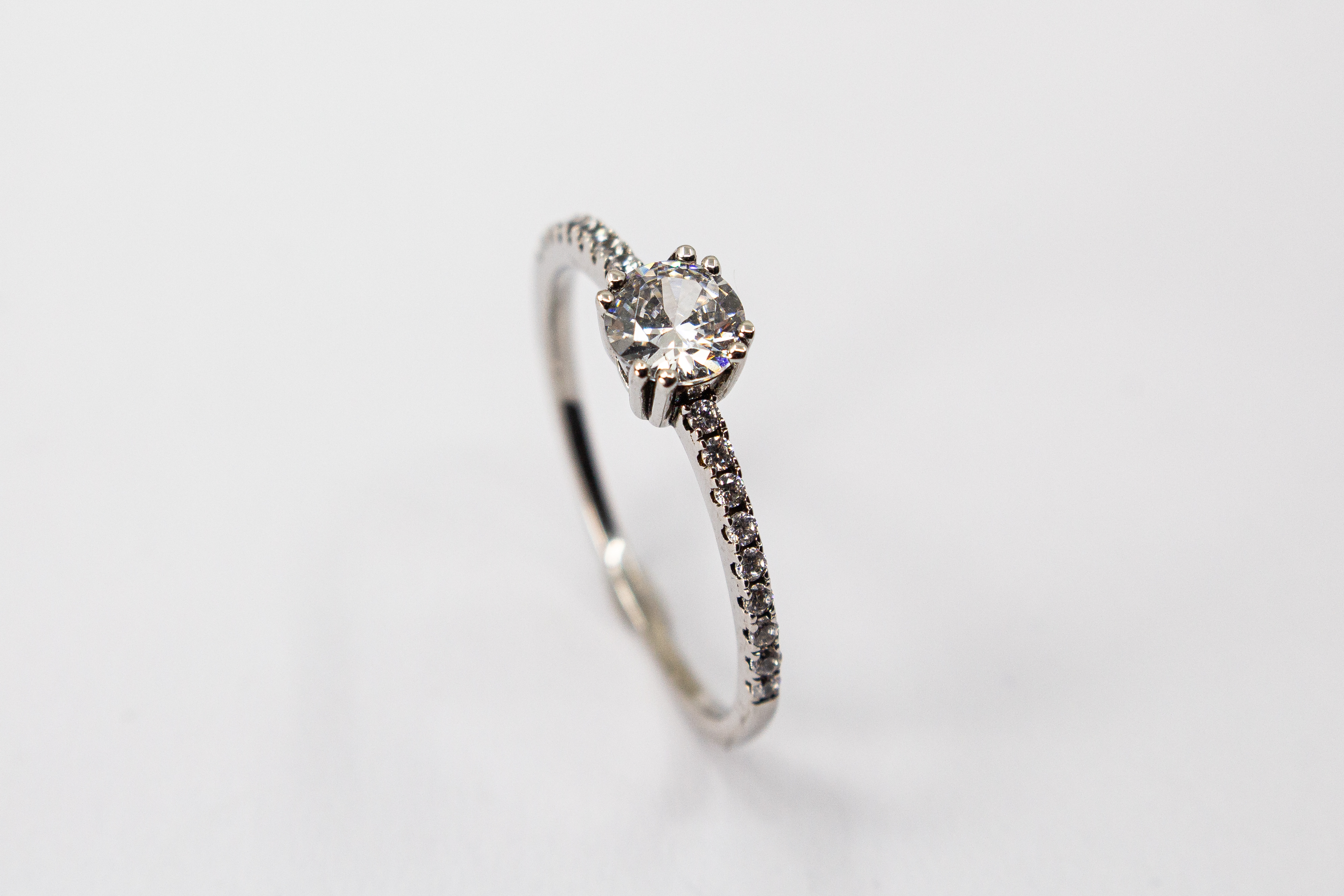Eleganter Solitärring aus rhodiniertem 925er Silber mit einem großen, in einer Vierer-Krappenfassung gehaltenen Zirkonia und einer mit kleinen Zirkoniasteinen besetzten Ringschiene im Onlineshop von Goldschmiede Regina Kraus.