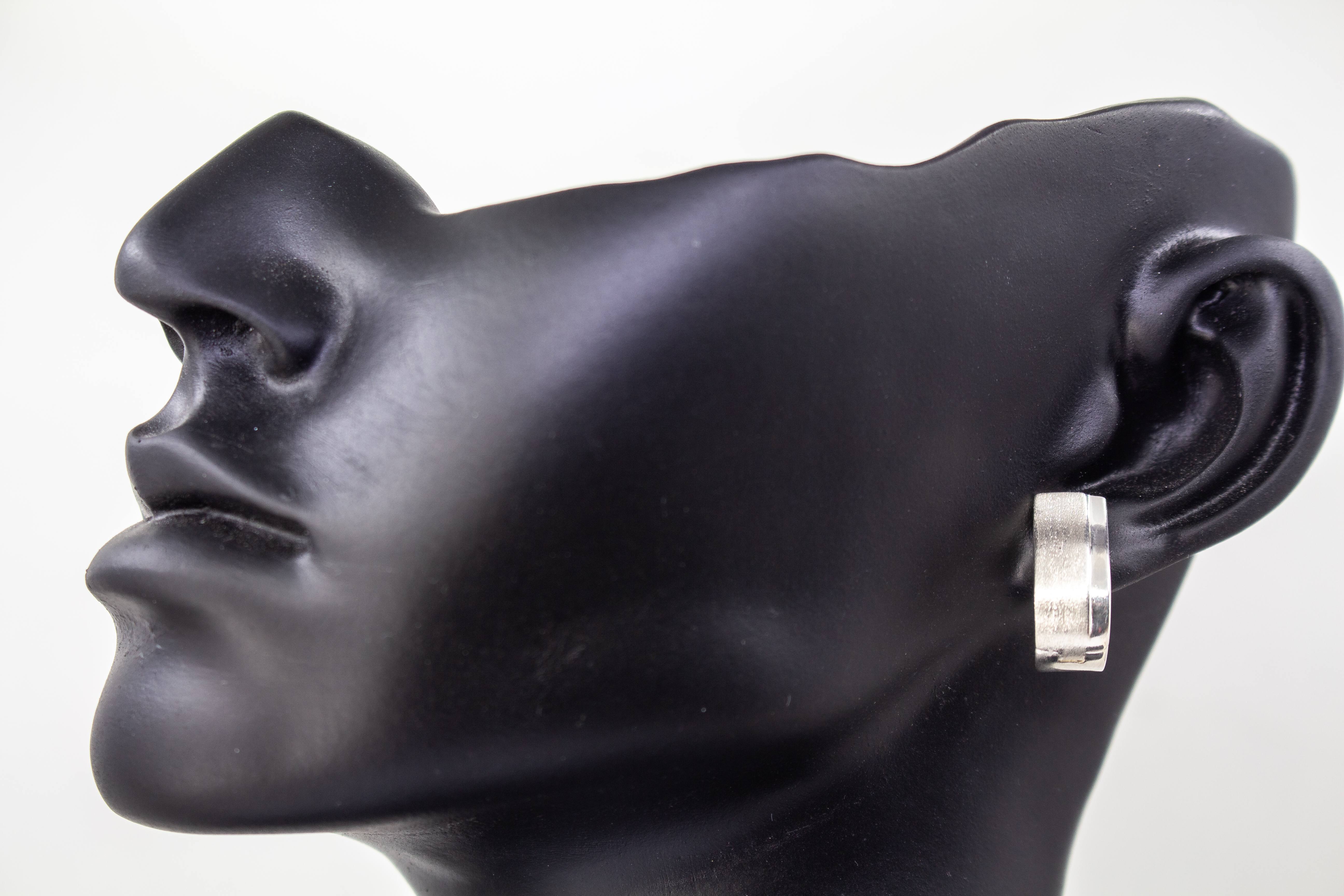 Breite Klappcreolen aus 925er Silber mit einer schwungvoll hochgezogenen, eismattierten Vorderseite und glänzend polierten Kanten im Onlineshop von Goldschmiede Regina Kraus.