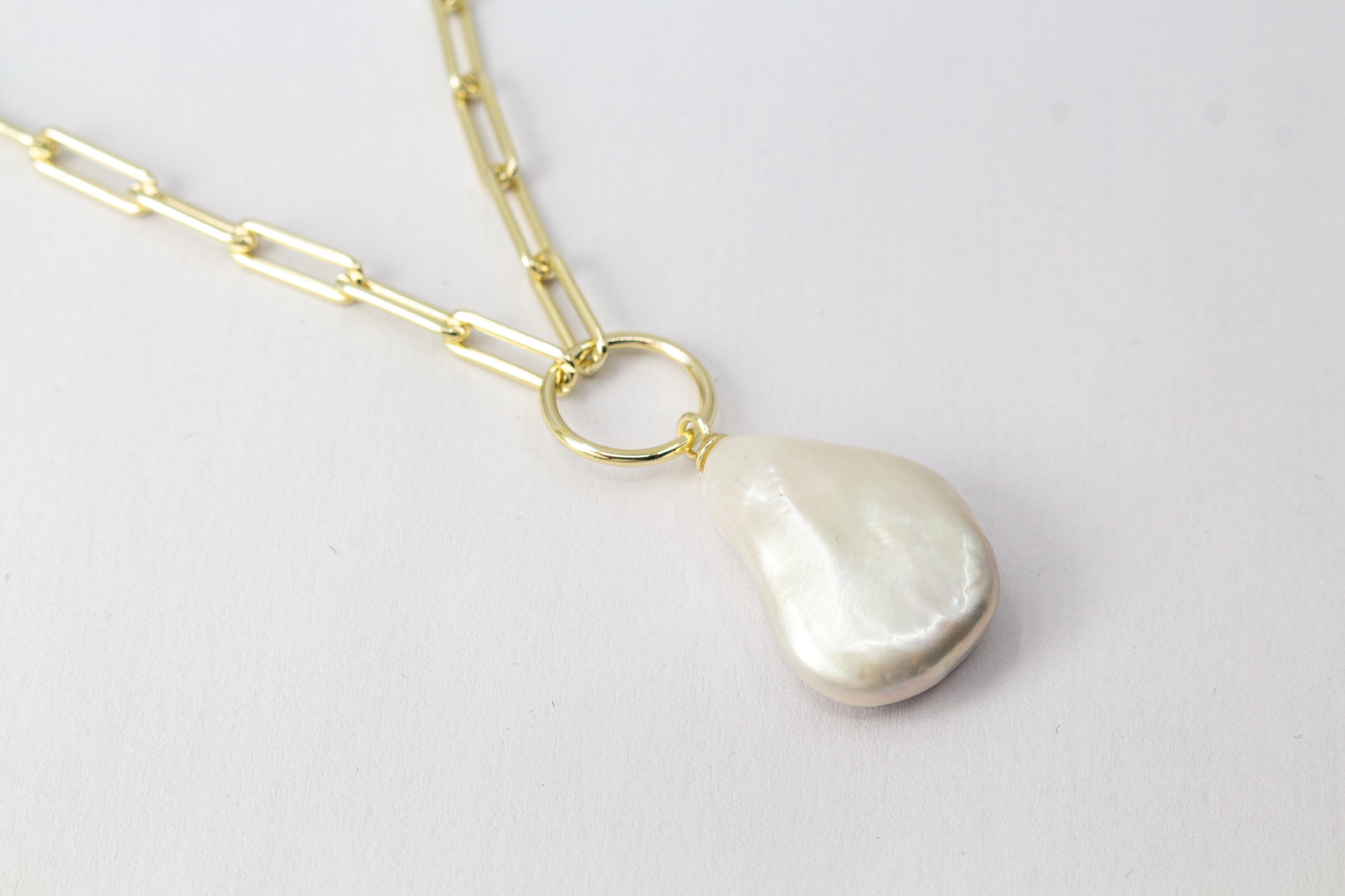Eine filigrane, hochwertig gelbvergoldete Halskette aus 925er Sterlingsilber von der Goldschmiede Regina Kraus. Als Anhänger dient eine edle, weiße Barock-Zuchtperle mit ihrer typischen, unregelmäßig gewachsenen Form und einem intensiv schimmernden Lüster