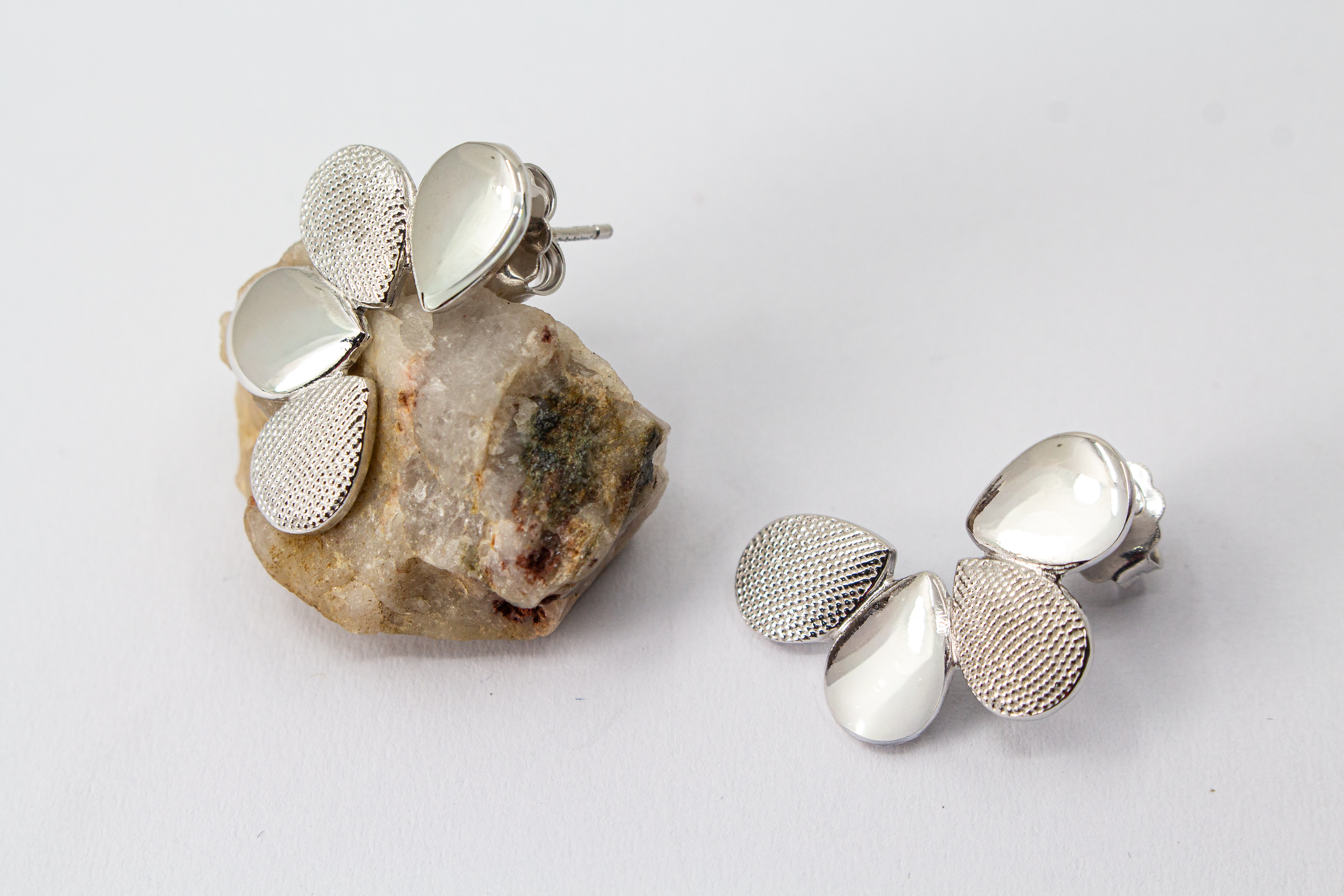 Moderne Ohrstecker der Cosmic Drop Serie von Diva Gioielli aus rhodiniertem 925 Silber. Die Ohrringe zeigen eine fächerförmige Anordnung von glatten und punktförmig strukturierten Tropfen
