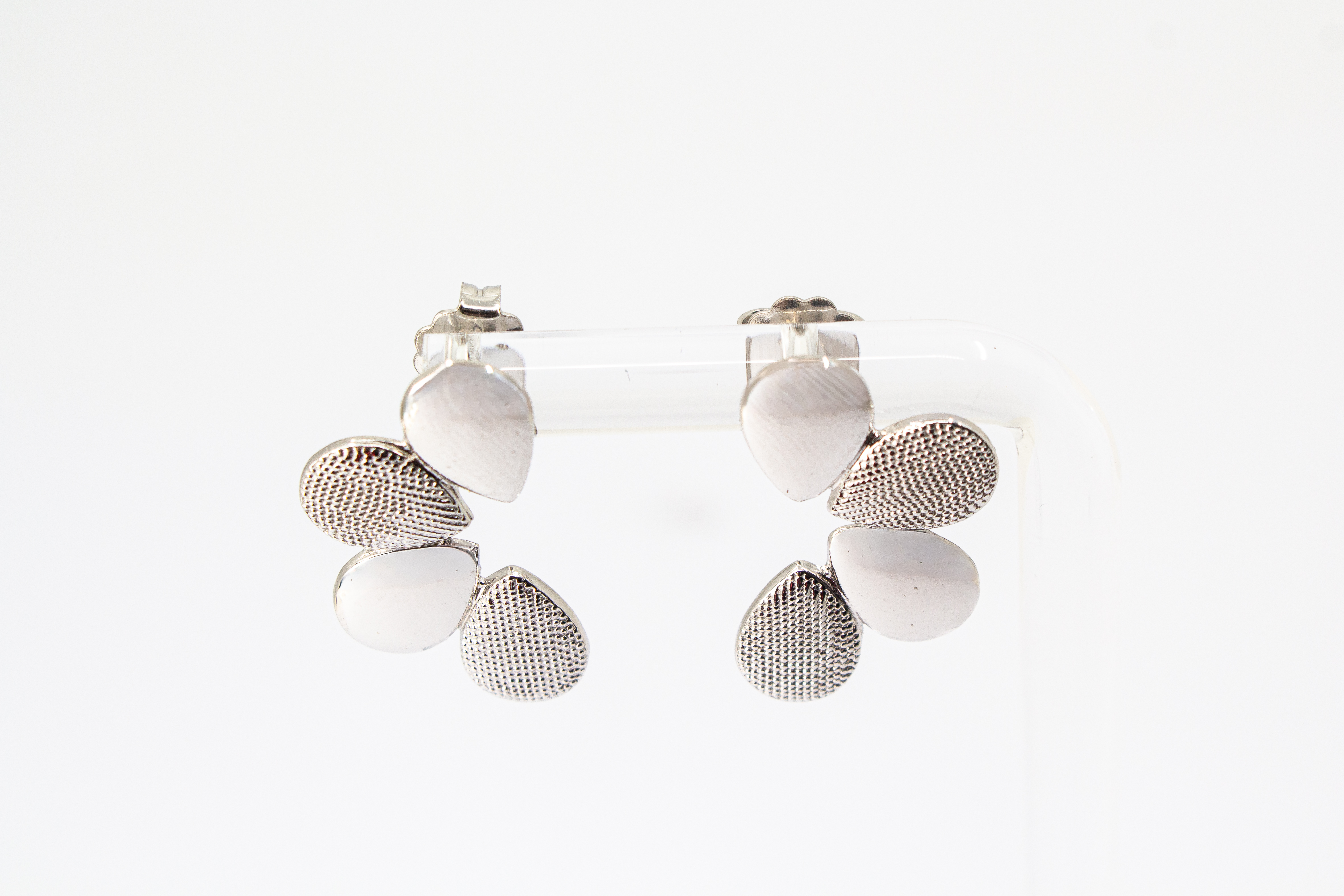 Moderne Ohrstecker der Cosmic Drop Serie von Diva Gioielli aus rhodiniertem 925 Silber. Die Ohrringe zeigen eine fächerförmige Anordnung von glatten und punktförmig strukturierten Tropfen