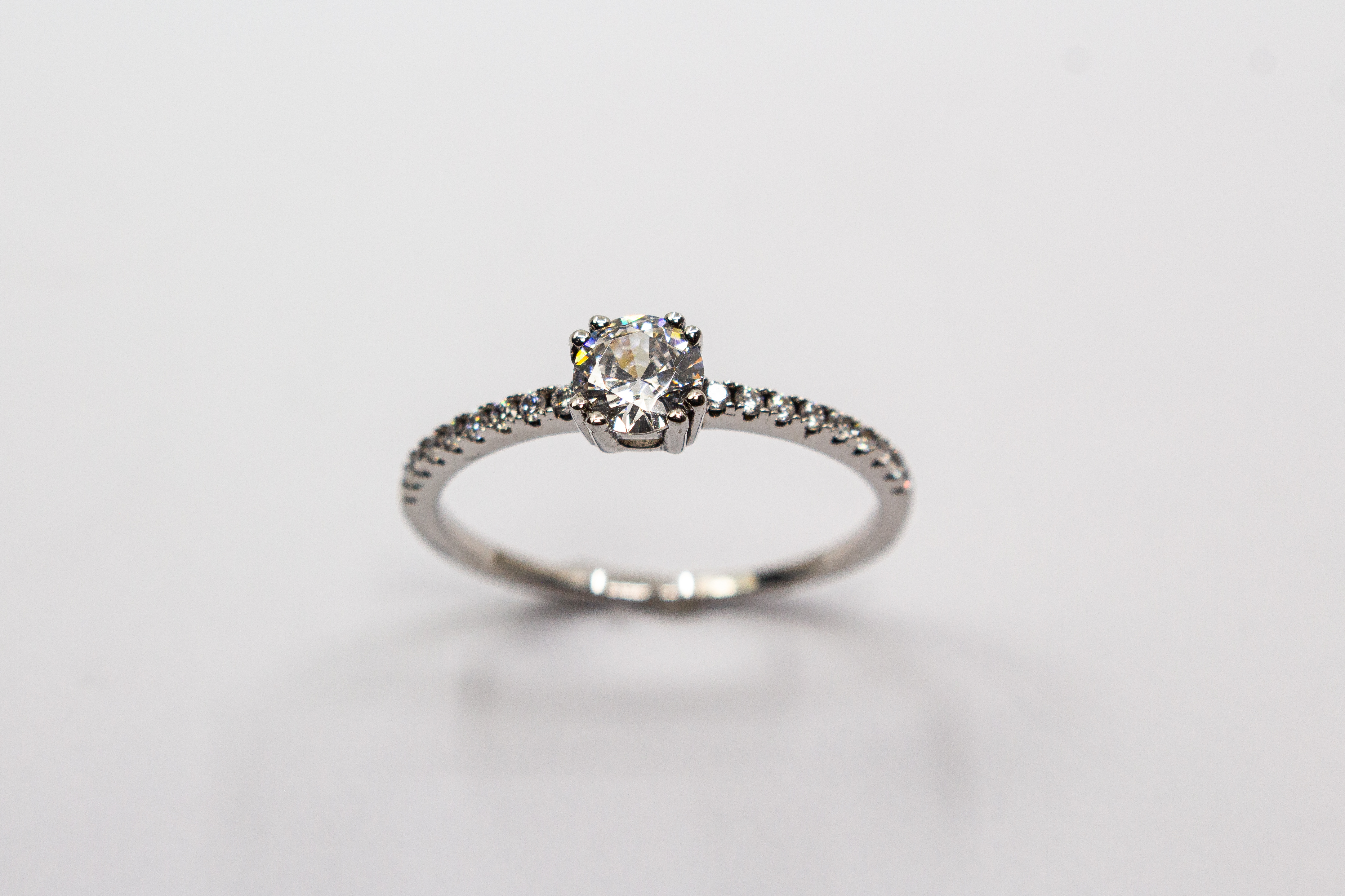 Eleganter Solitärring aus rhodiniertem 925er Silber mit einem großen, in einer Vierer-Krappenfassung gehaltenen Zirkonia und einer mit kleinen Zirkoniasteinen besetzten Ringschiene im Onlineshop von Goldschmiede Regina Kraus.