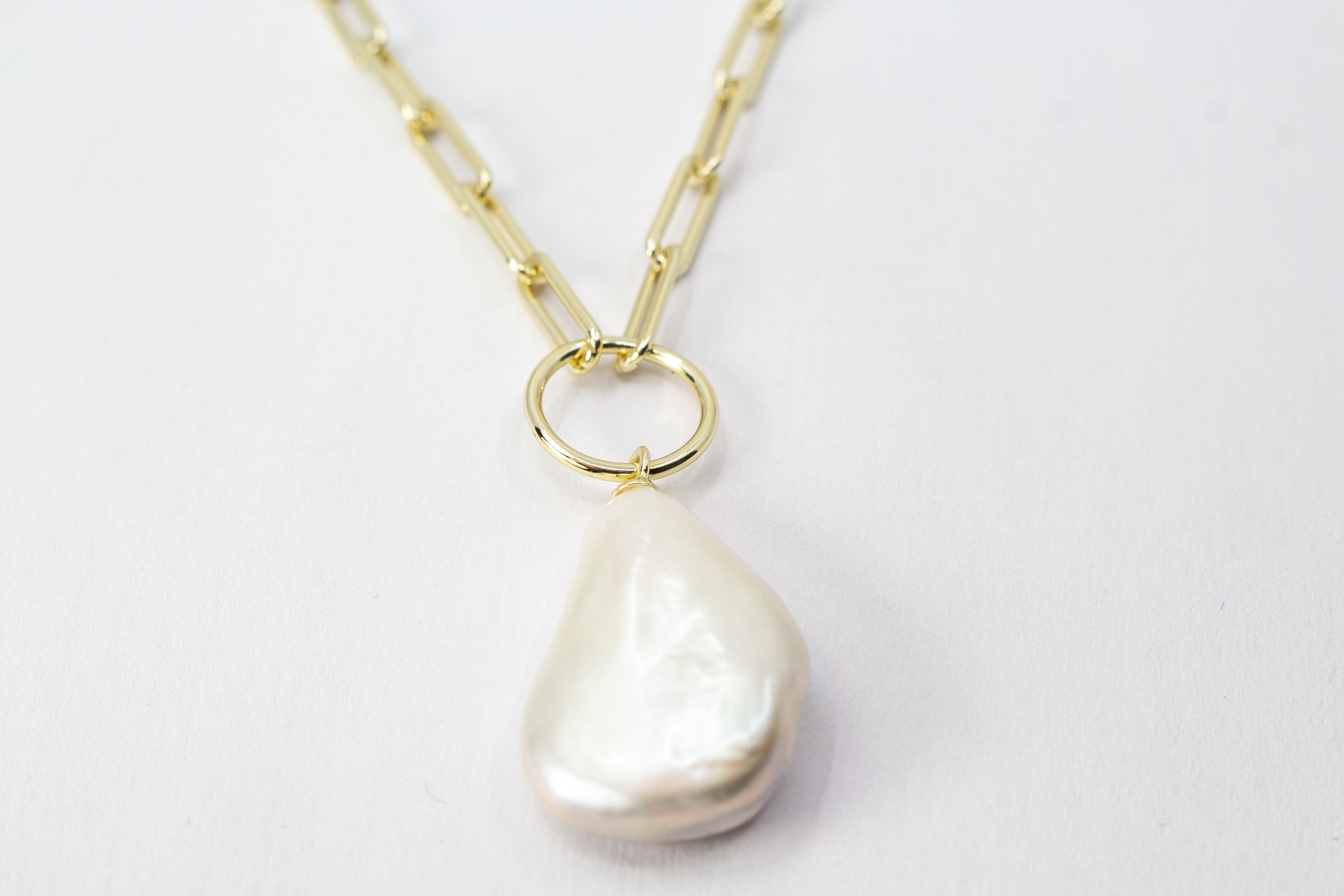 Eine filigrane, hochwertig gelbvergoldete Halskette aus 925er Sterlingsilber von der Goldschmiede Regina Kraus. Als Anhänger dient eine edle, weiße Barock-Zuchtperle mit ihrer typischen, unregelmäßig gewachsenen Form und einem intensiv schimmernden Lüster