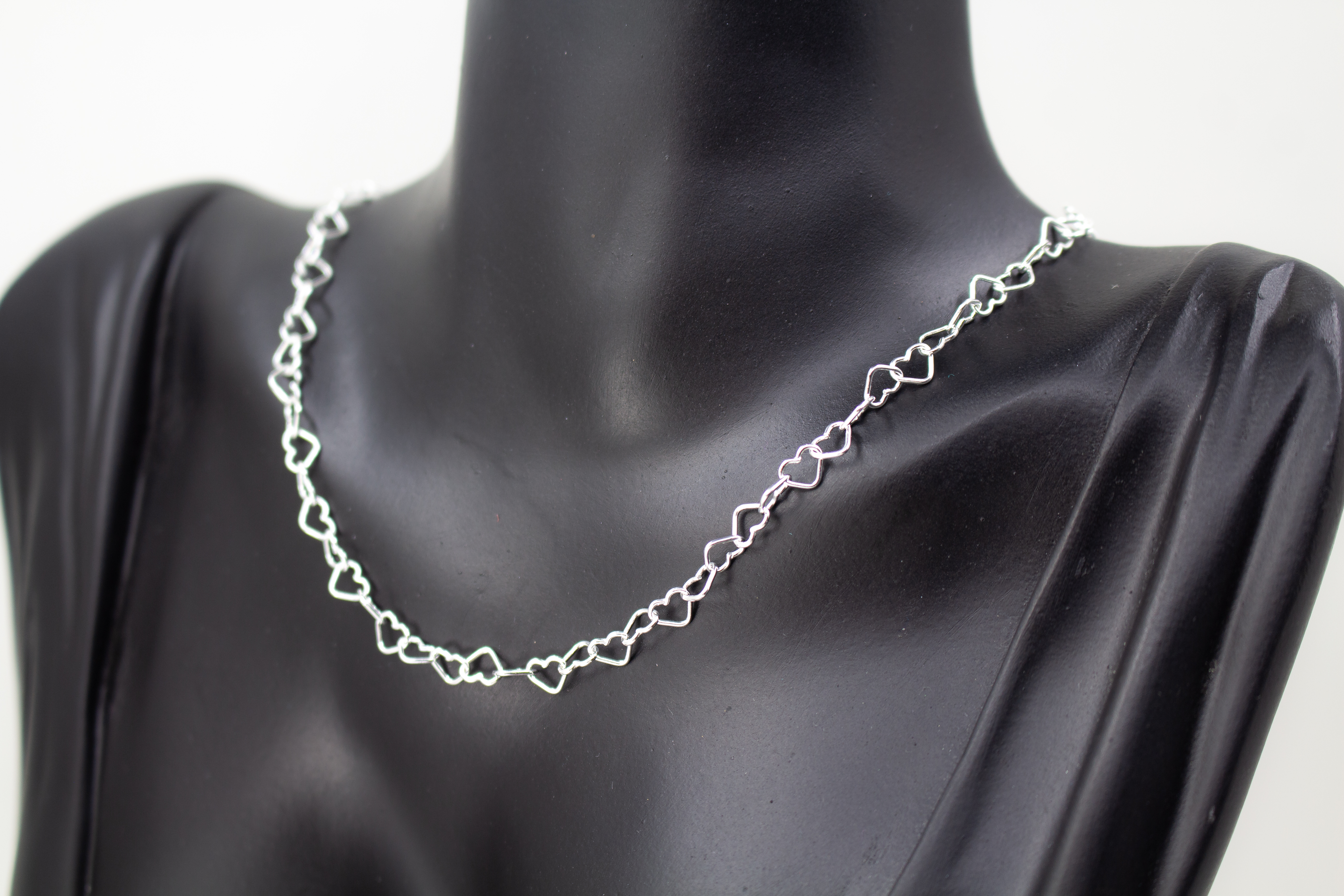 Zarte Halskette „Herz an Herz“ aus 925er Sterlingsilber, gefertigt aus einer Reihe kleiner, miteinander verbundener offener Herzen aus dem Onlineshop der Goldschmiede Regina Kraus.