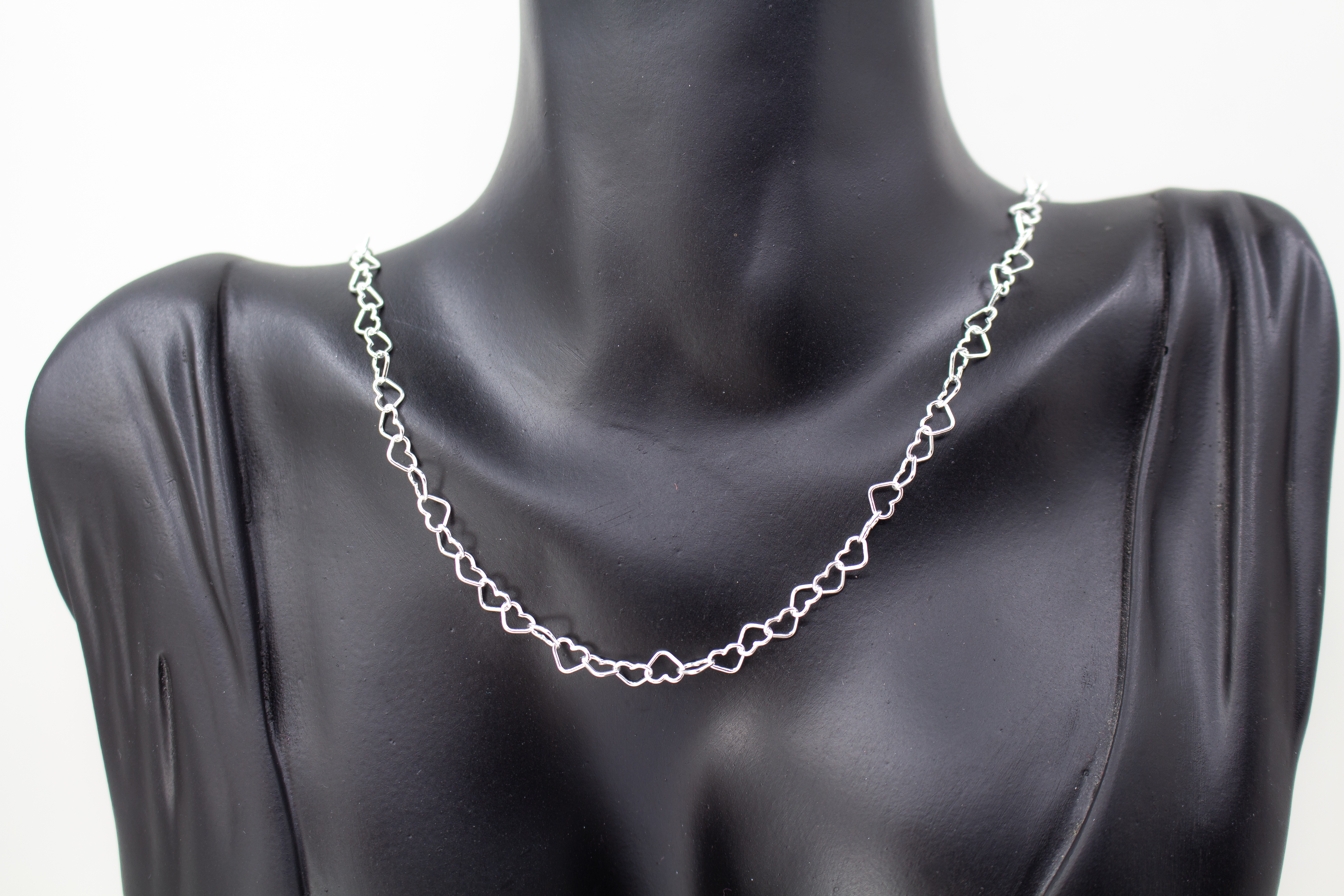 Zarte Halskette „Herz an Herz“ aus 925er Sterlingsilber, gefertigt aus einer Reihe kleiner, miteinander verbundener offener Herzen aus dem Onlineshop der Goldschmiede Regina Kraus.