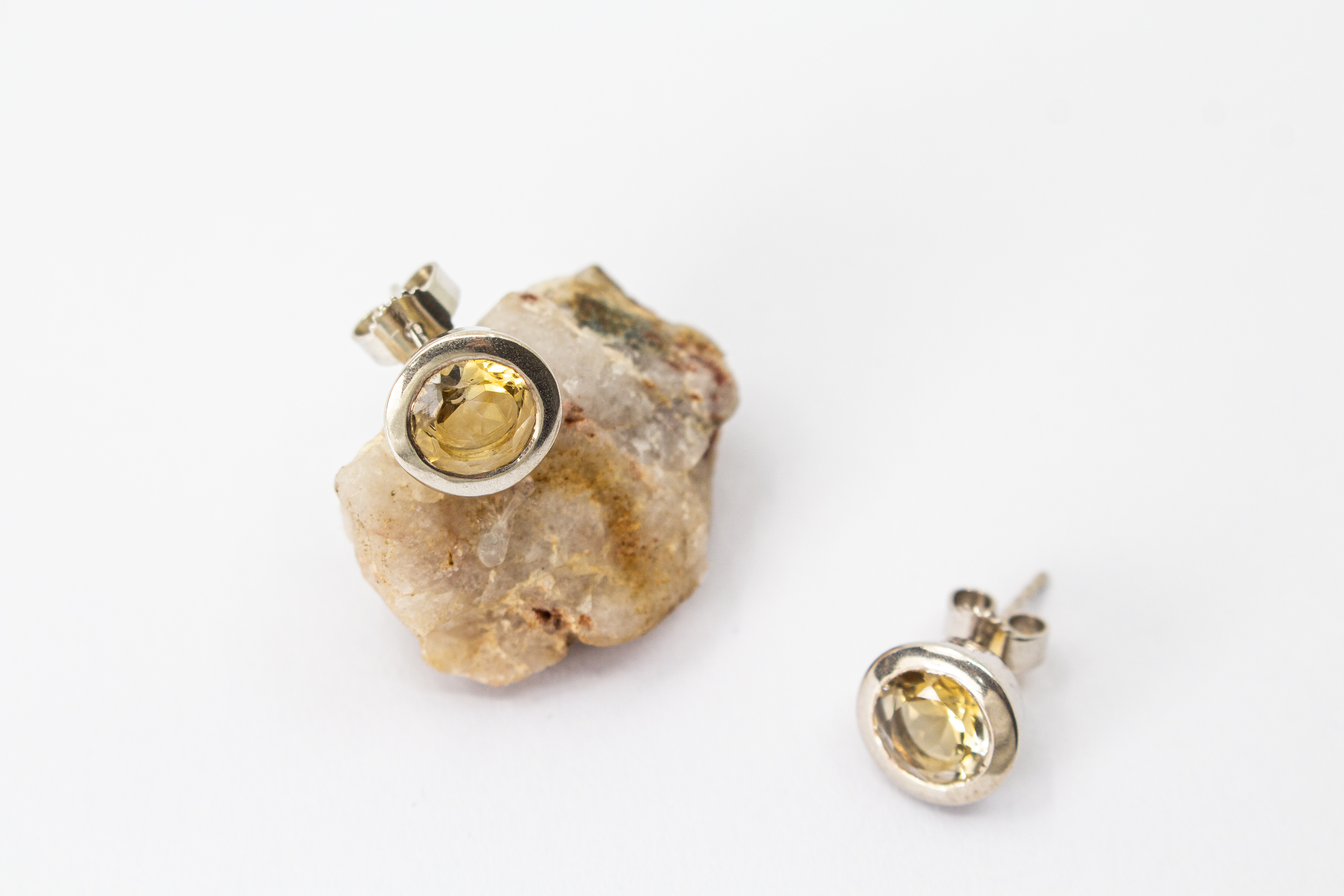 klassische, runde Ohrstecker aus glänzendem 925 Sterling Silber mit einem facettierten, hellgelben Citrin-Edelstein in einer glatten Zargenfassung aus dem Online-Shop der Goldschmiede Regina Kraus.