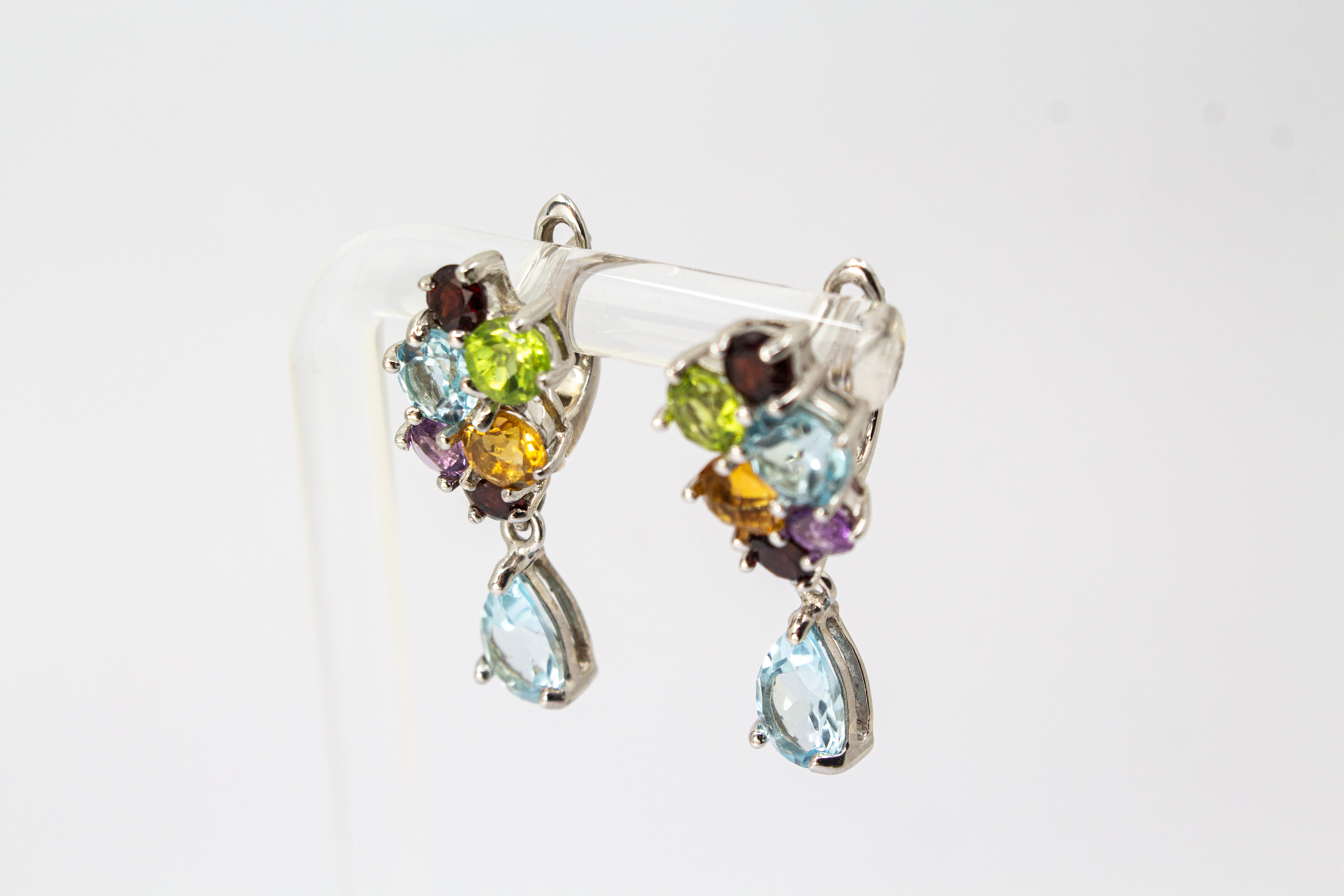 Elegante Multicolor-Edelstein-Ohrhänger aus rhodiniertem 925 Silber von der Goldschmiede Regina Kraus. Die detailreichen Ohrringe zeigen ein farbenfrohes Cluster aus rund facettierten Steinen wie Amethyst, Peridot, Citrin und Granat, gefolgt von einem bew