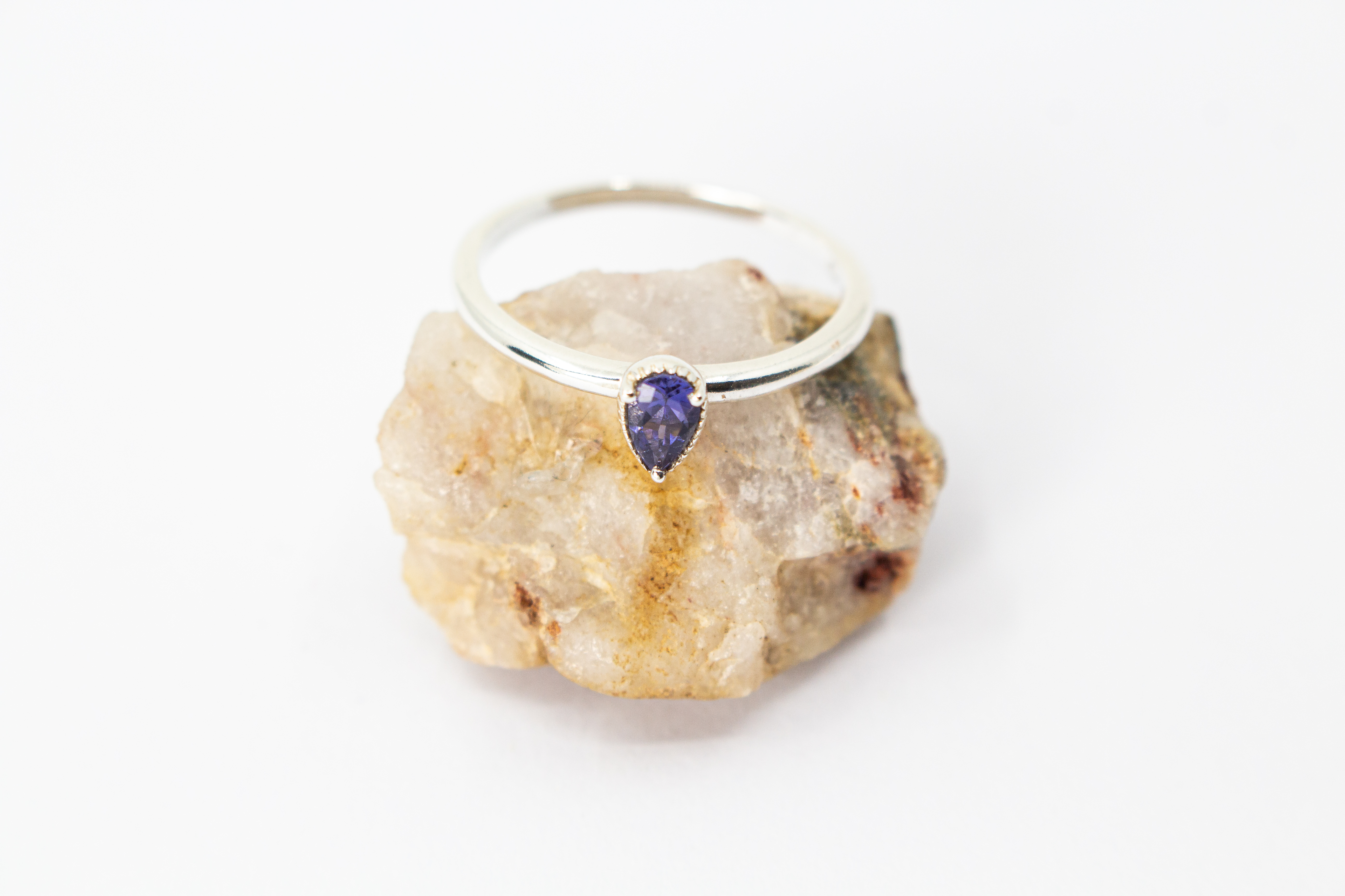 Filigraner Damenring aus glänzendem 925 Sterling Silber mit einem kleinen, tropfenförmigen, blau-violetten Iolith-Edelstein in einer fein verzierten Zargenfassung aus dem Online-Shop der Goldschmiede Regina Kraus.