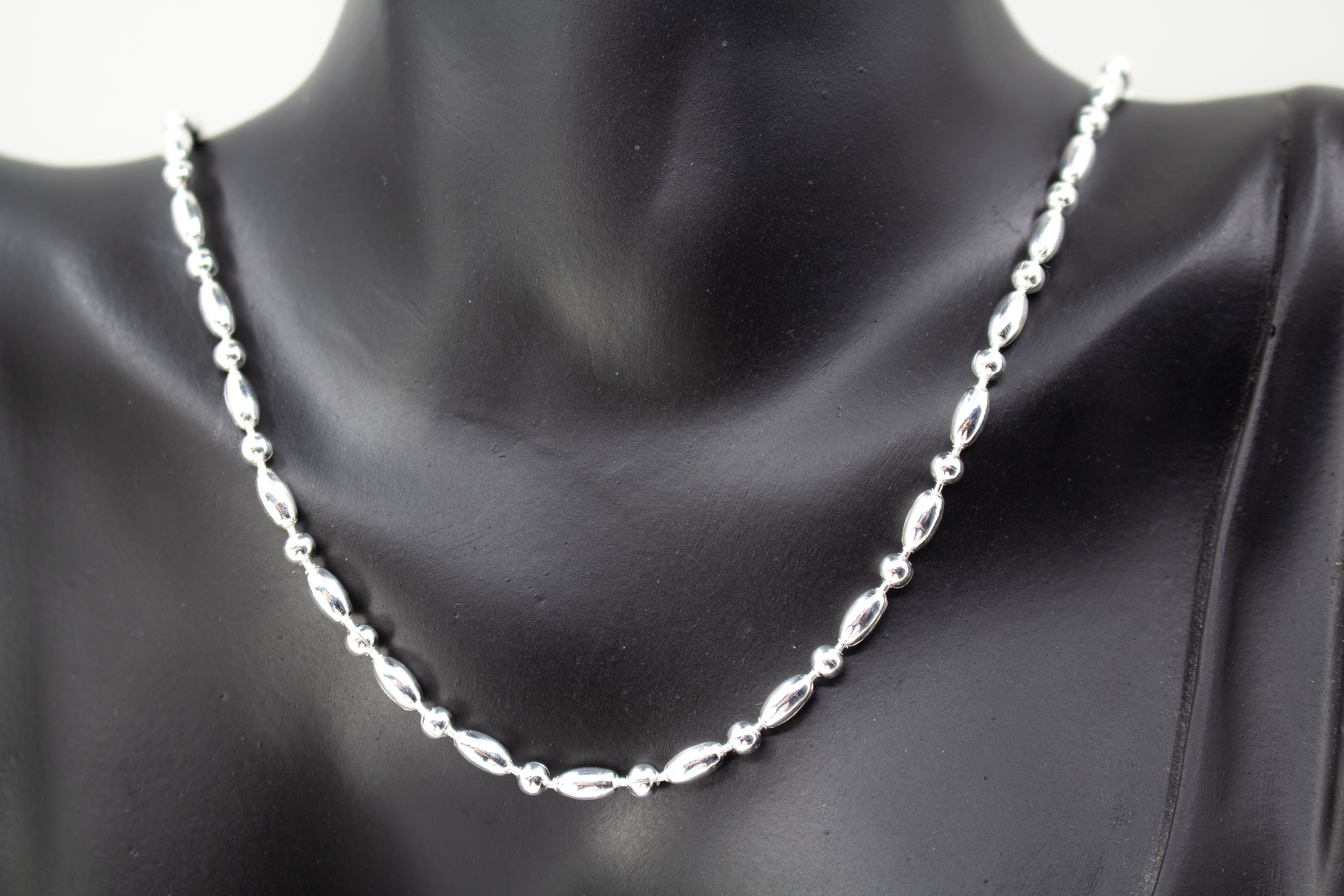 Filigrane Silberkette aus hochglanzpoliertem 925er Sterlingsilber mit einem rhythmischen Wechsel aus Oliven- und Kugel-Elementen auf hellem Untergrund, exklusiv erhältlich im Schmuck-Onlineshop der Goldschmiede Regina Kraus.
