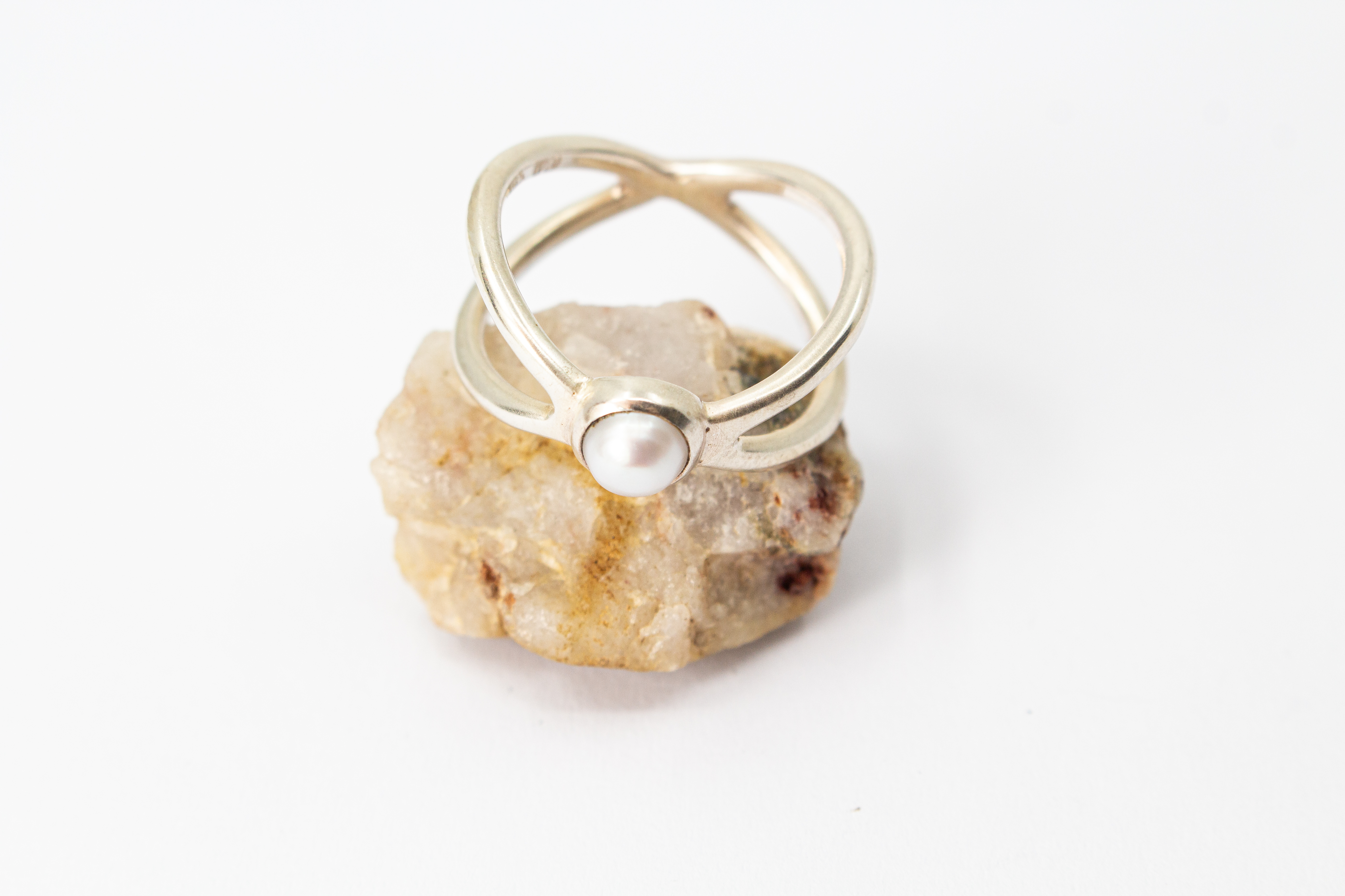 Geschwungener Damenring aus poliertem 925 Sterlingsilber mit einer runden, mittig eingefassten weißen Süßwasserzuchtperle von der Goldschmiede Regina Kraus.