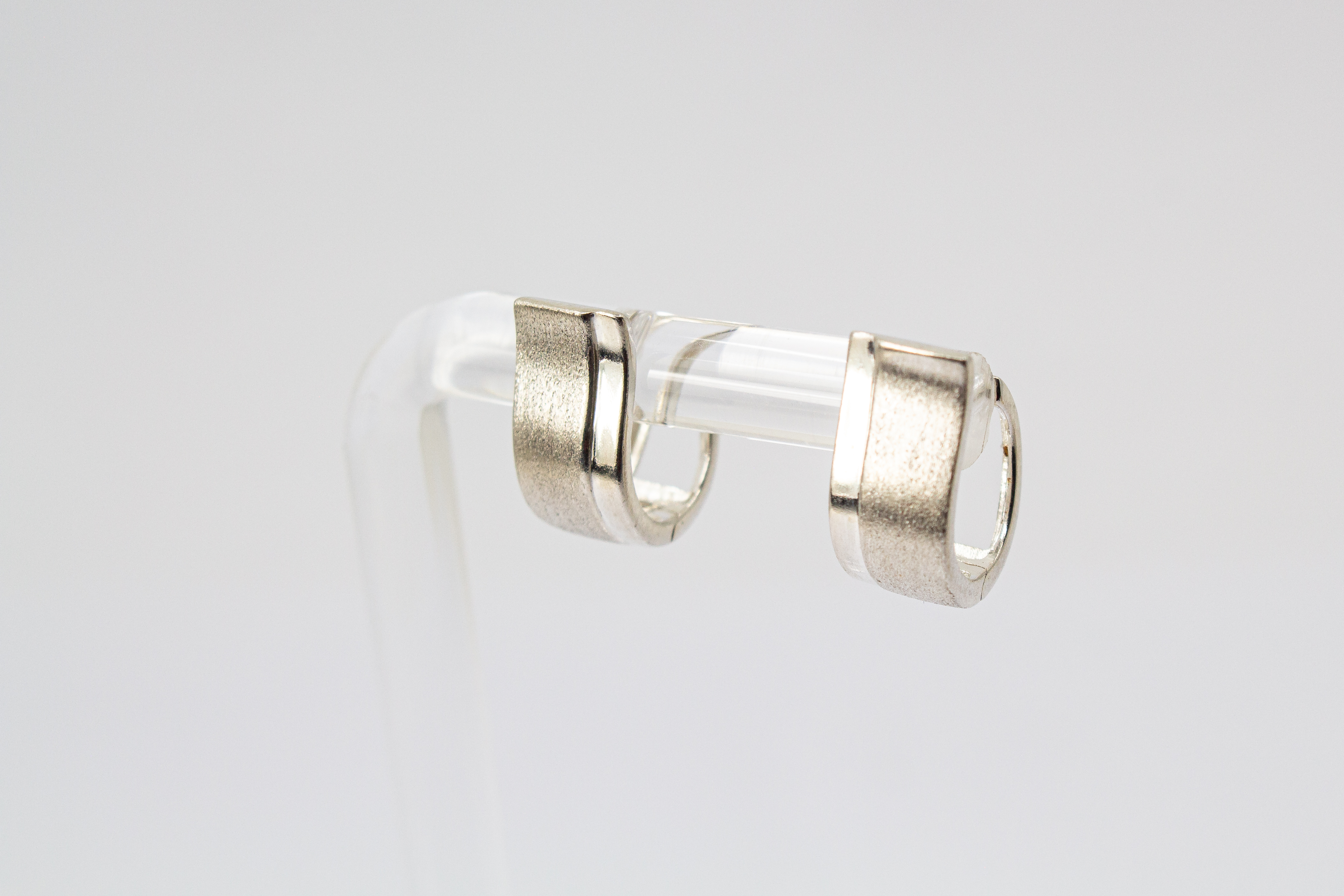 Breite Klappcreolen aus 925er Silber mit einer schwungvoll hochgezogenen, eismattierten Vorderseite und glänzend polierten Kanten im Onlineshop von Goldschmiede Regina Kraus.