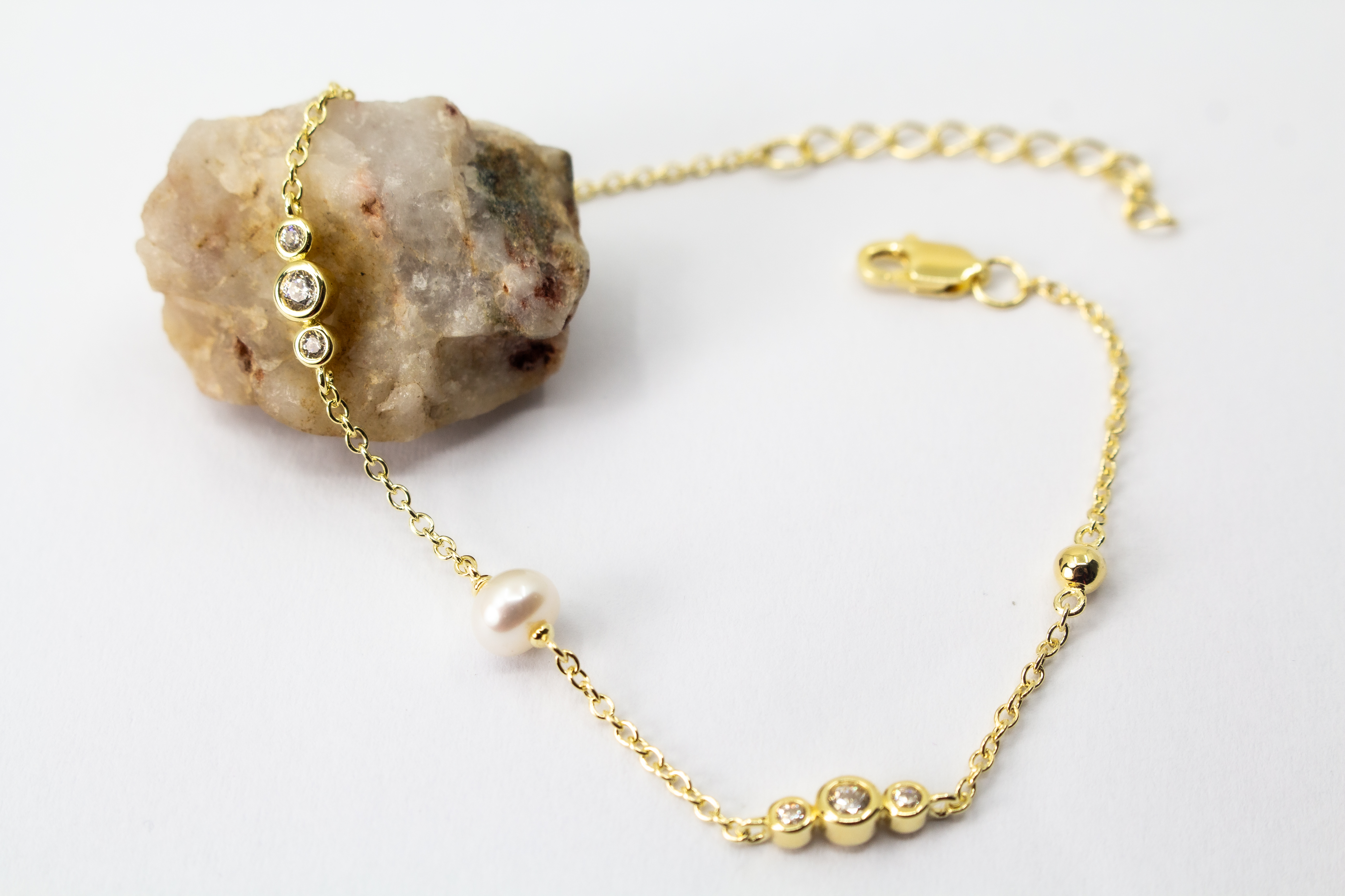 Edles Armband der Goldschmiede Regina Kraus aus vergoldetem 925er Silber mit einer zentralen Süßwasserperle, flankiert von funkelnden Zirkonia-Elementen und kleinen Goldkugeln