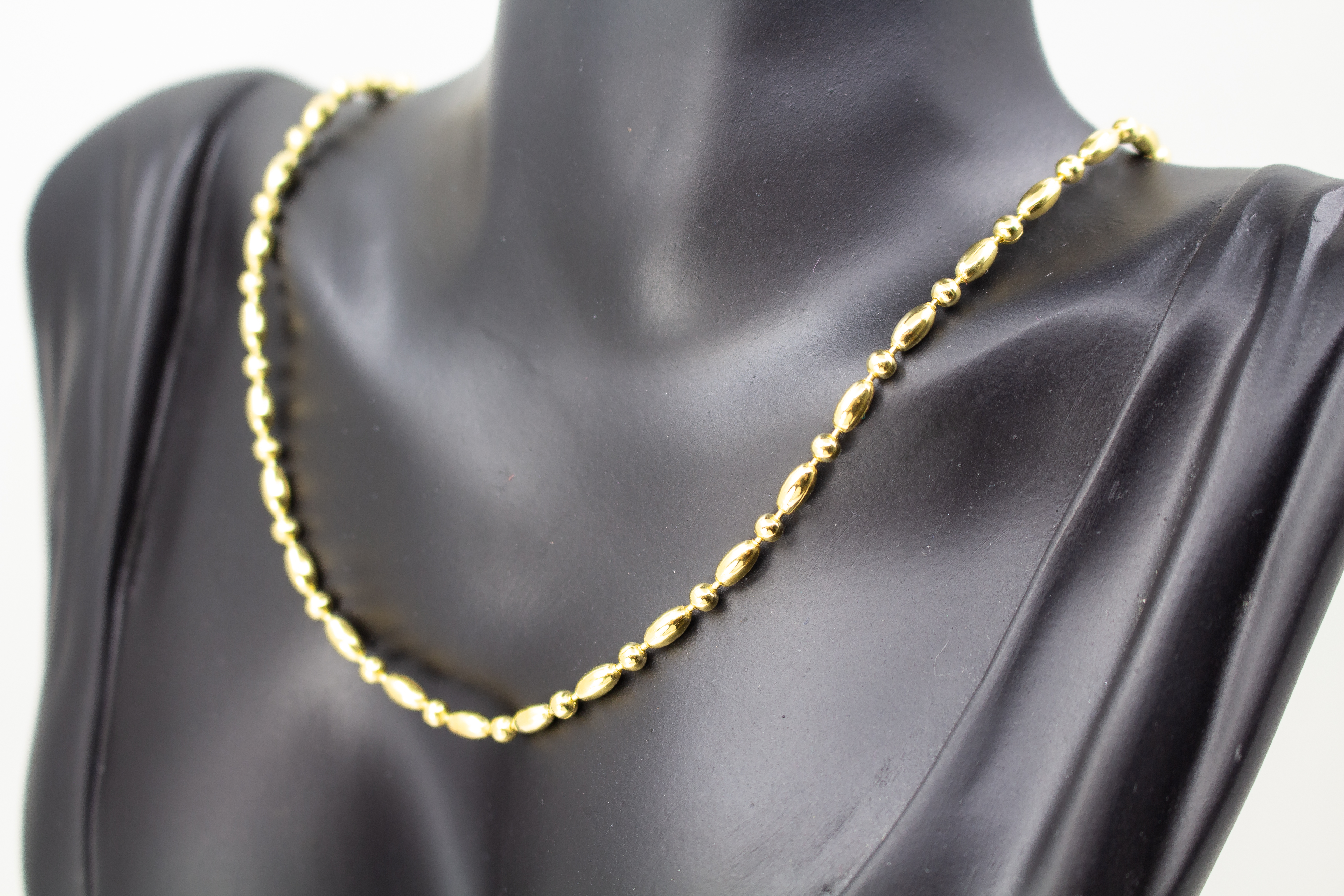 Elegantes, hochwertig vergoldetes Collier aus 925er Sterlingsilber mit einer 20 Mikron Vergoldung, gestaltet in einem rhythmischen Wechsel aus polierten Oliven- und Kugel-Elementen auf hellem Hintergrund, aus dem Schmuck-Onlineshop der Goldschmiede Regina