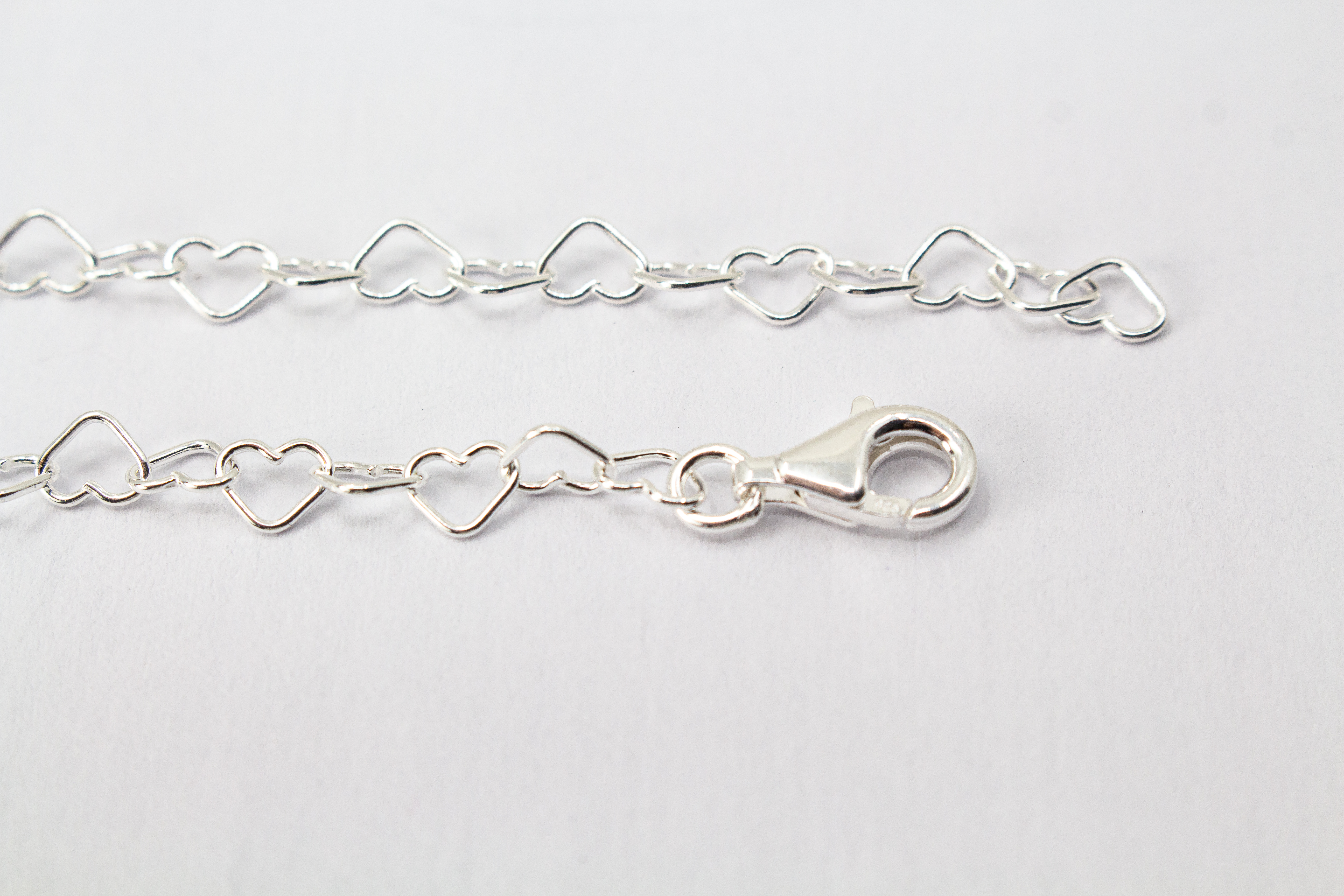 Zarte Halskette „Herz an Herz“ aus 925er Sterlingsilber, gefertigt aus einer Reihe kleiner, miteinander verbundener offener Herzen aus dem Onlineshop der Goldschmiede Regina Kraus.