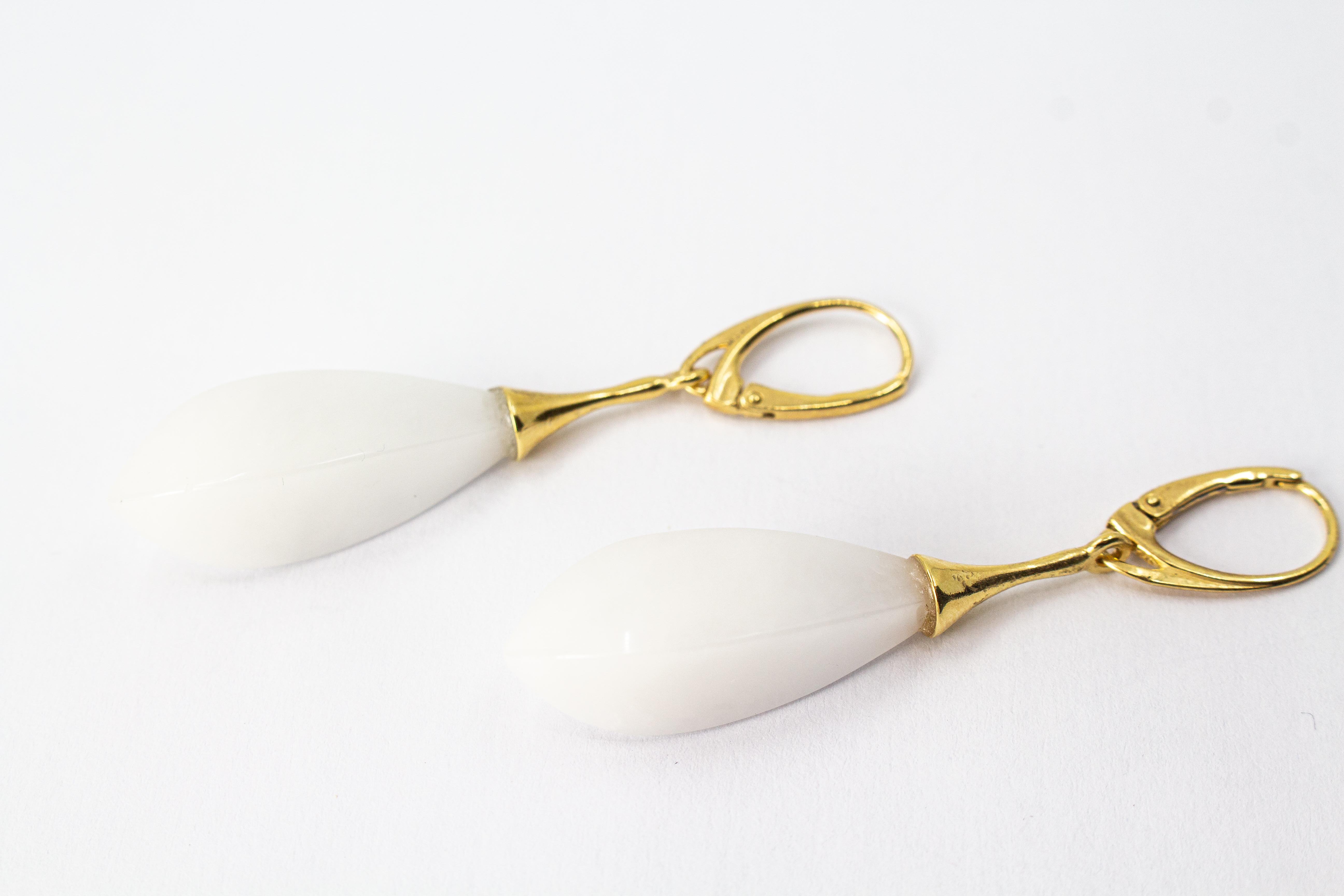 Elegante Tropfen-Ohrhänger mit weißem, porzellanartigen Kascholong-Edelstein und einer vergoldeten Brisur aus 925er Sterlingsilber von der Goldschmiede Regina Kraus.