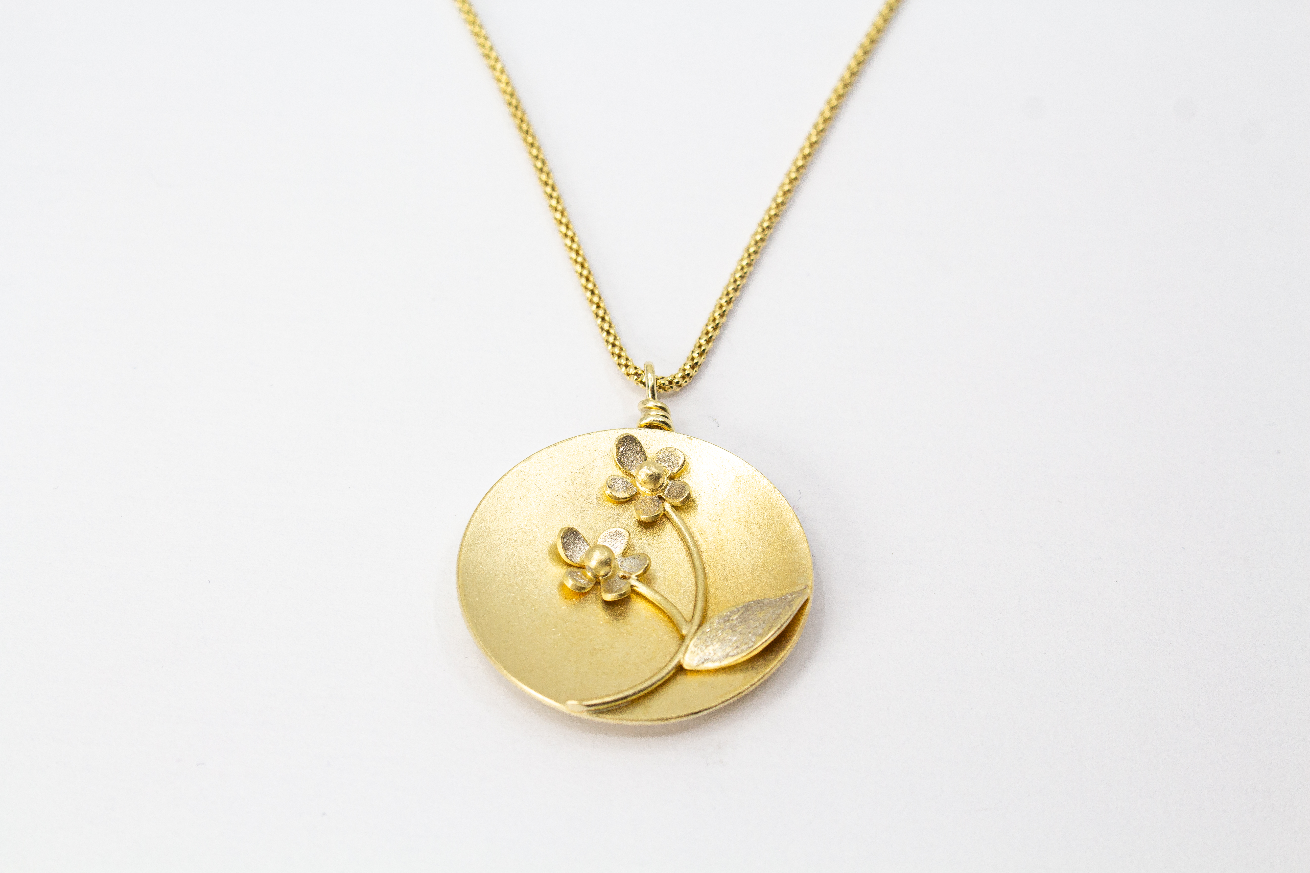 Feine Halskette mit rundem, matt vergoldetem Medaillon-Anhänger aus 20 Mikron plattiertem 925er Sterlingsilber, verziert mit einem plastischen Blumen-Motiv mit zwei Blüten und einem Blatt