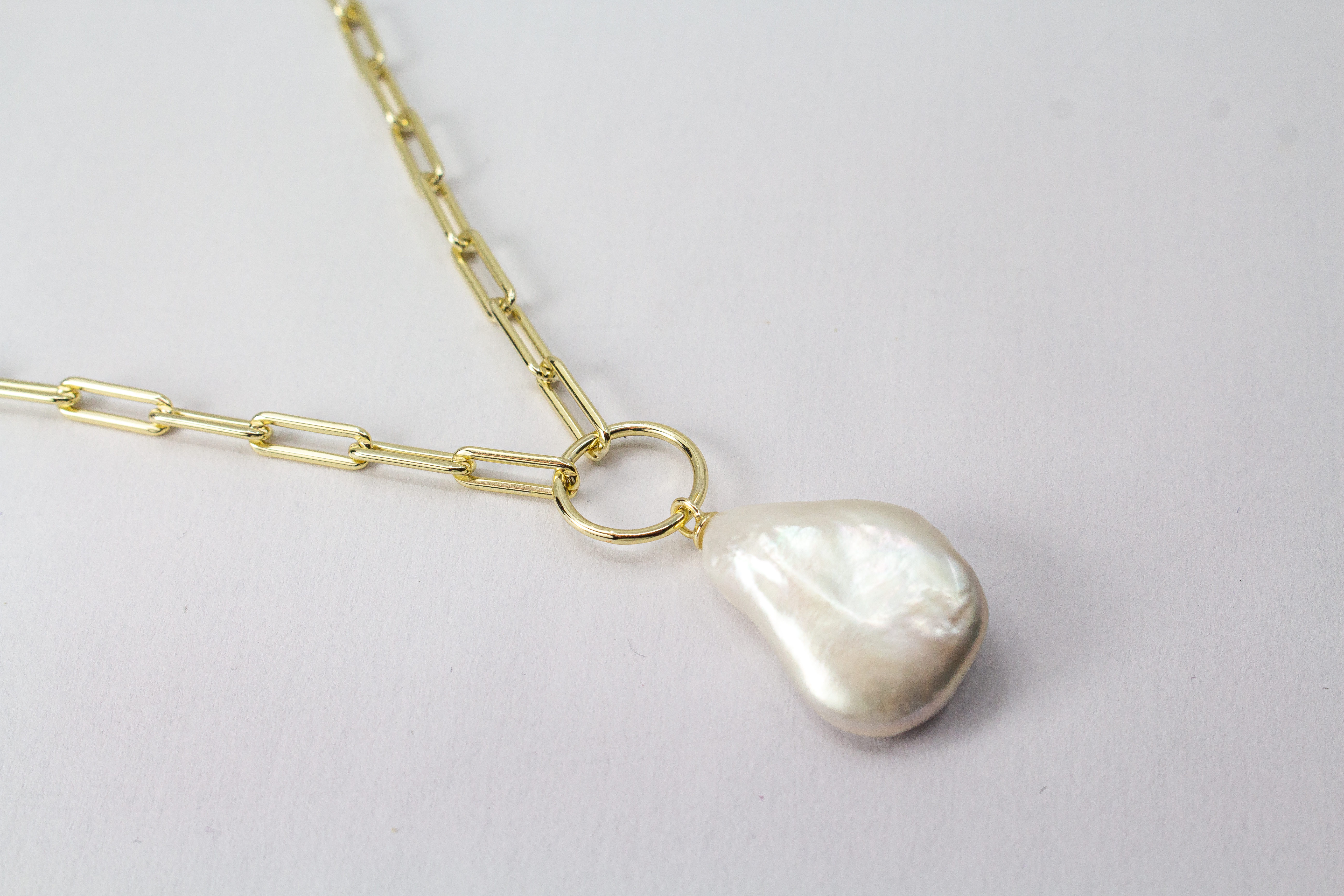 Eine filigrane, hochwertig gelbvergoldete Halskette aus 925er Sterlingsilber von der Goldschmiede Regina Kraus. Als Anhänger dient eine edle, weiße Barock-Zuchtperle mit ihrer typischen, unregelmäßig gewachsenen Form und einem intensiv schimmernden Lüster