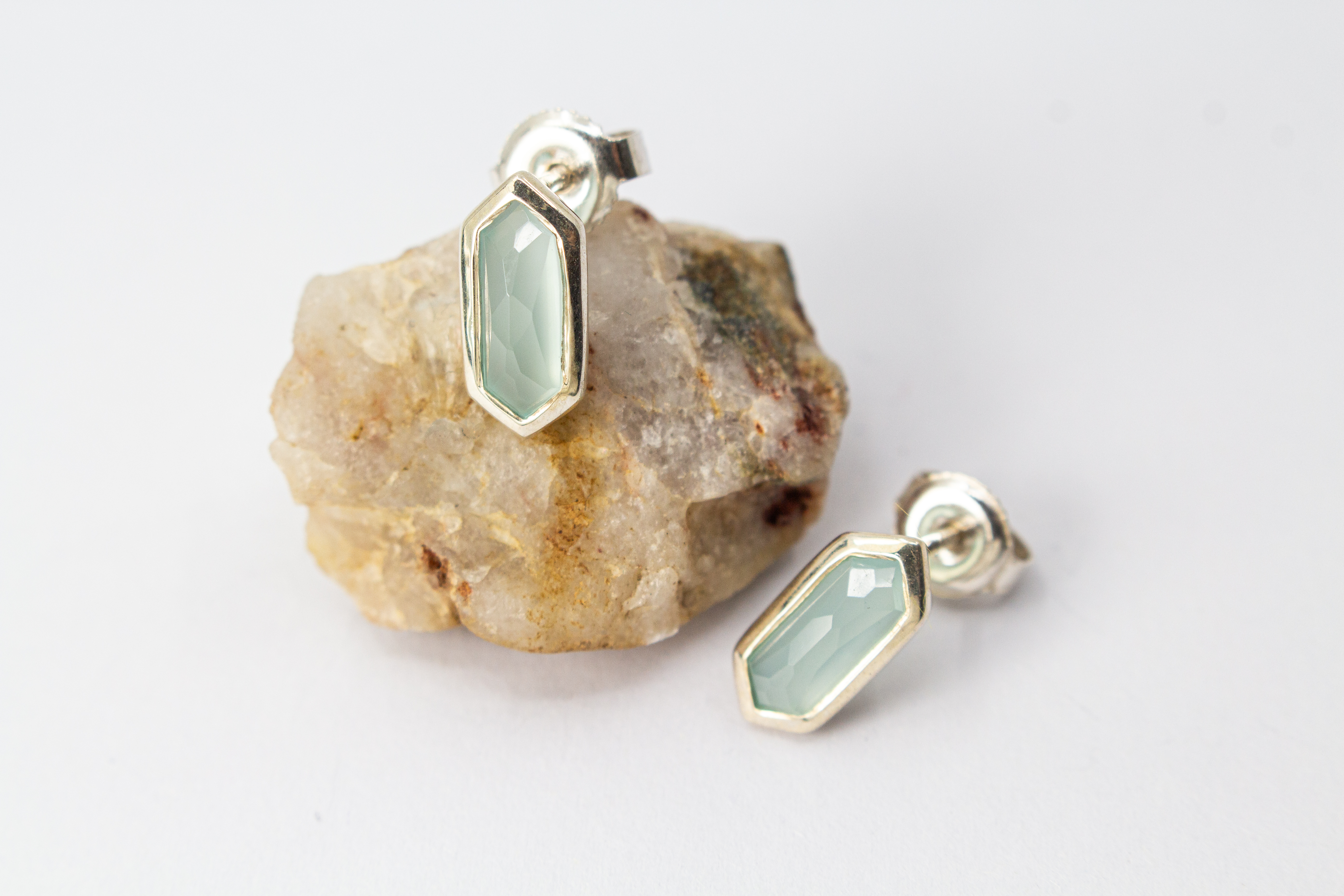 geometrische Ohrstecker aus glänzendem 925 Sterling Silber mit einem facettierten, sechseckigen Chalcedon-Edelstein in hellem Pastellblau aus dem Online-Shop der Goldschmiede Regina Kraus.