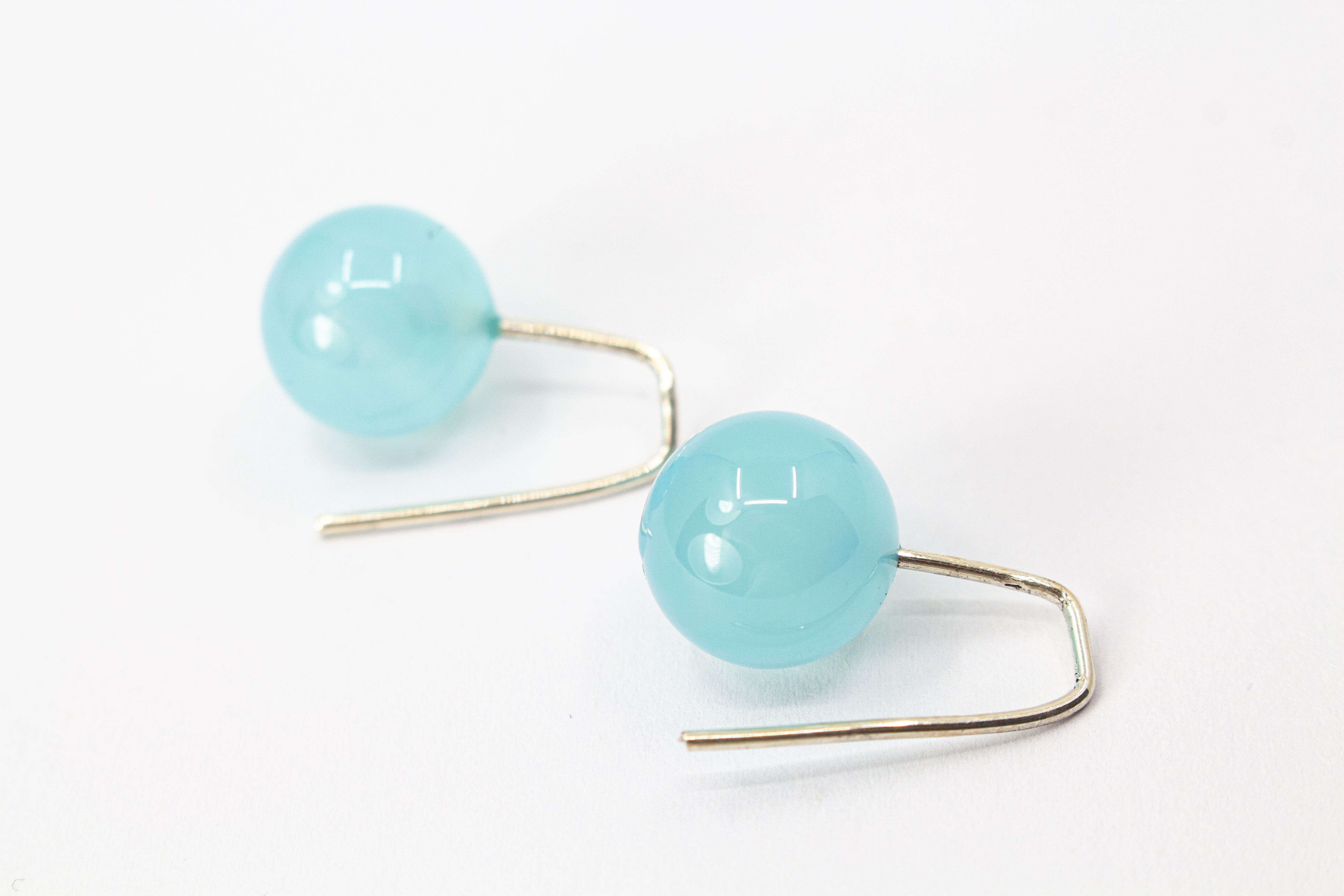 Minimalistische Ohrhänger aus feinen 925 Sterling Silberbügeln mit je einer glatten, hellblauen Chalcedon-Edelsteinkugel aus dem Online-Shop der Goldschmiede Regina Kraus