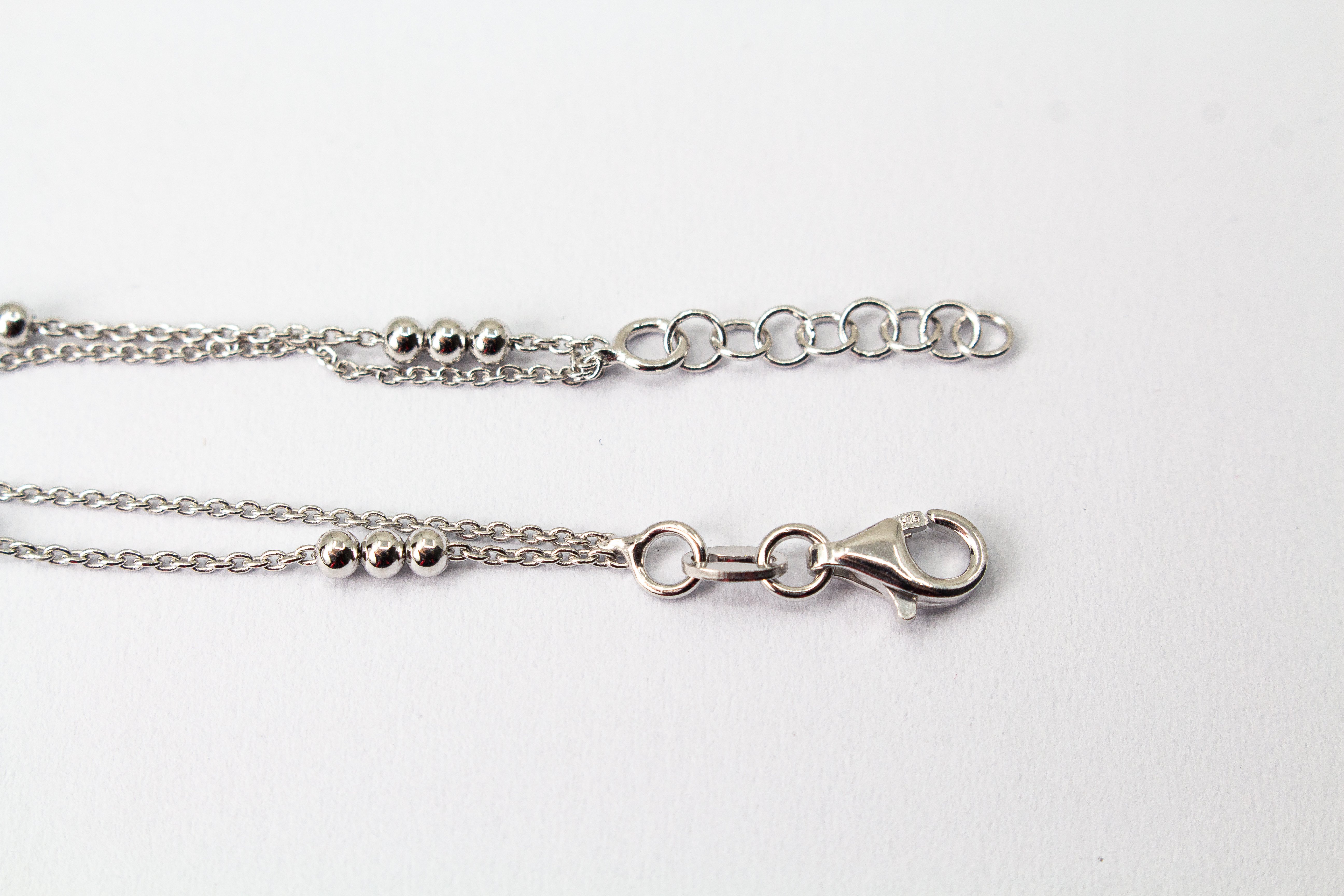 Zweireihiges Armband der Goldschmiede Regina Kraus aus hochwertigem rhodiniertem 925er Silber mit kleinen Silberkugeln in Dreiergruppen auf feinen Ankerketten.
