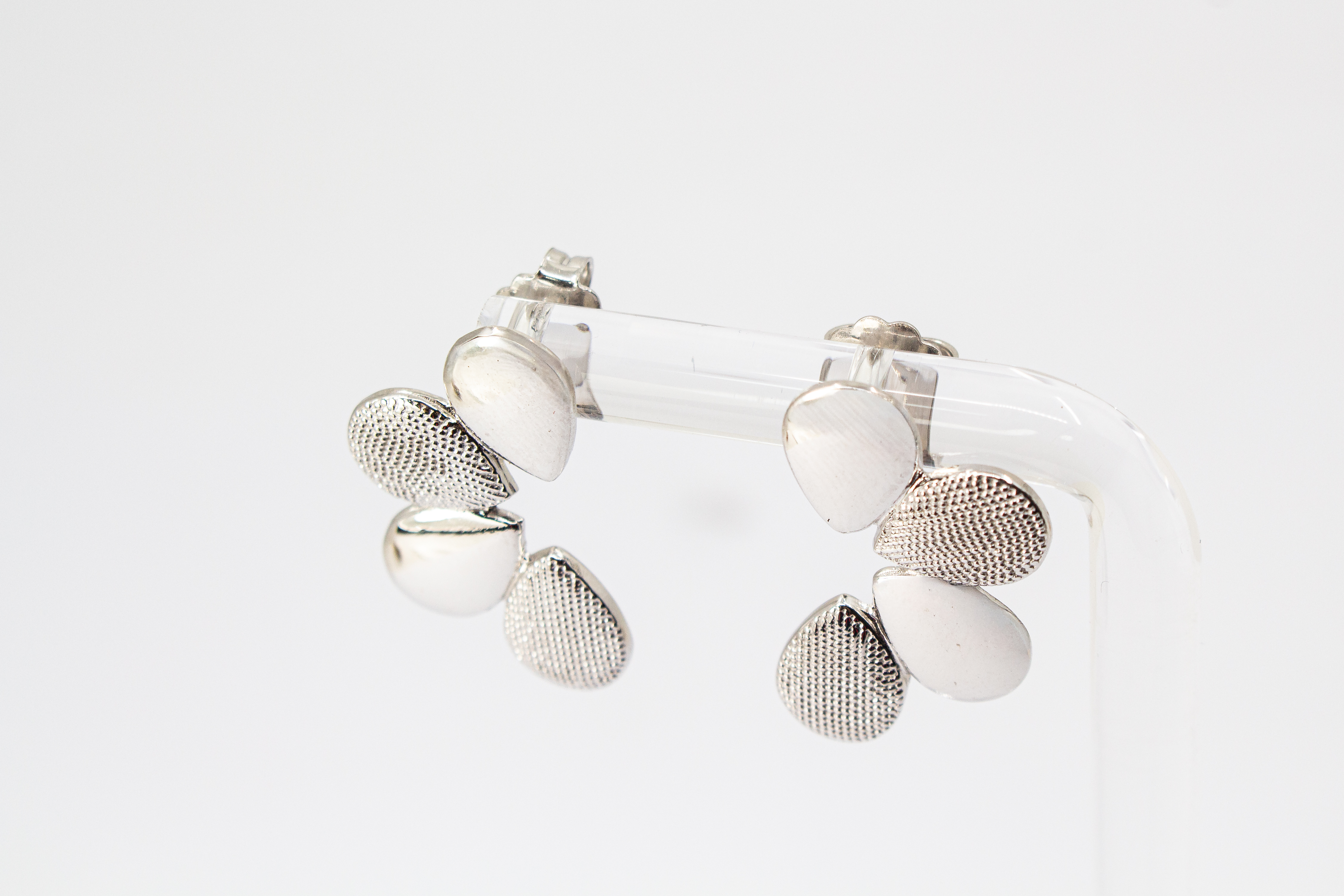 Moderne Ohrstecker der Cosmic Drop Serie von Diva Gioielli aus rhodiniertem 925 Silber. Die Ohrringe zeigen eine fächerförmige Anordnung von glatten und punktförmig strukturierten Tropfen