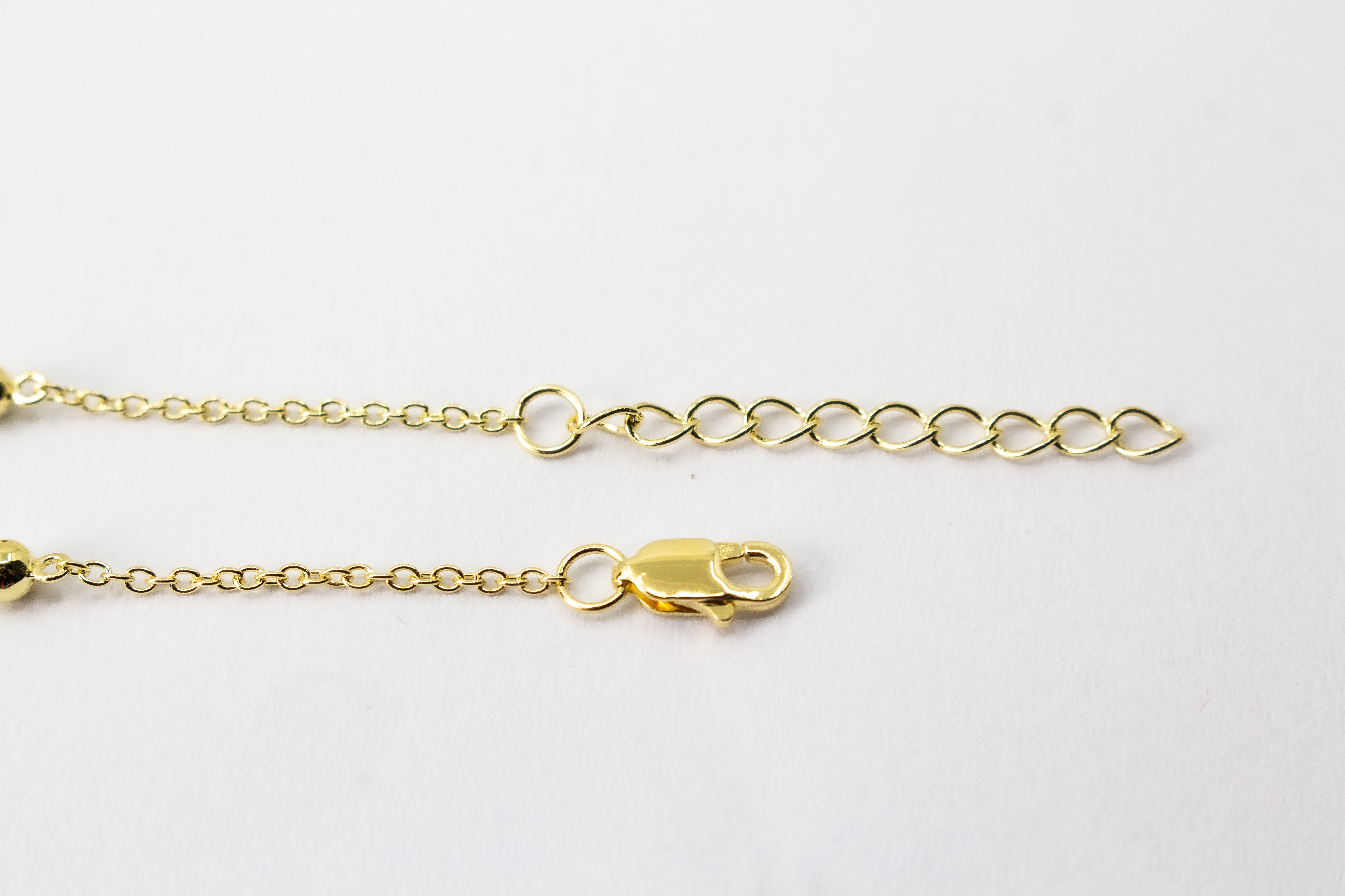 Edles Armband der Goldschmiede Regina Kraus aus vergoldetem 925er Silber mit einer zentralen Süßwasserperle, flankiert von funkelnden Zirkonia-Elementen und kleinen Goldkugeln
