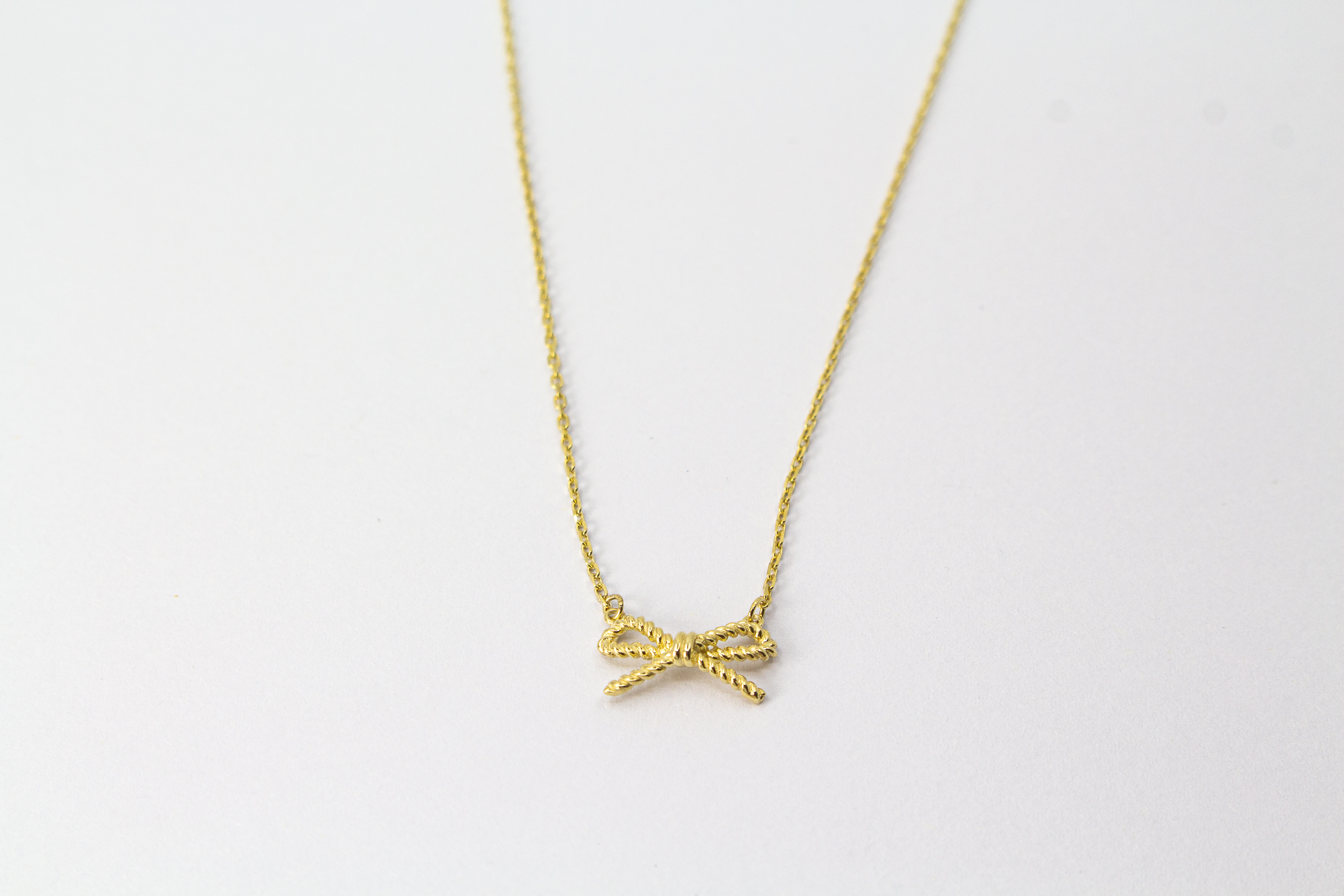 Collier „Schleifenzauber“ aus vergoldetem 925er Sterlingsilber mit filigranem Schleifenanhänger in elegantem, zeitlosem Design.